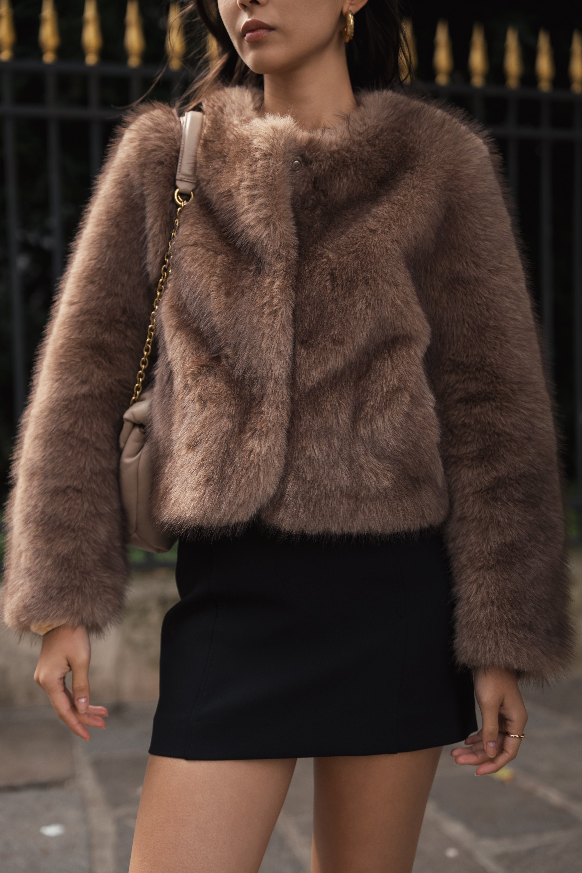 Manteau court en fausse fourrure femme Escandelle Paris, coloris brun, col rond, fermeture à pressions dissimulées, coupe élégante et poils longs doux.
#couleur_taupe