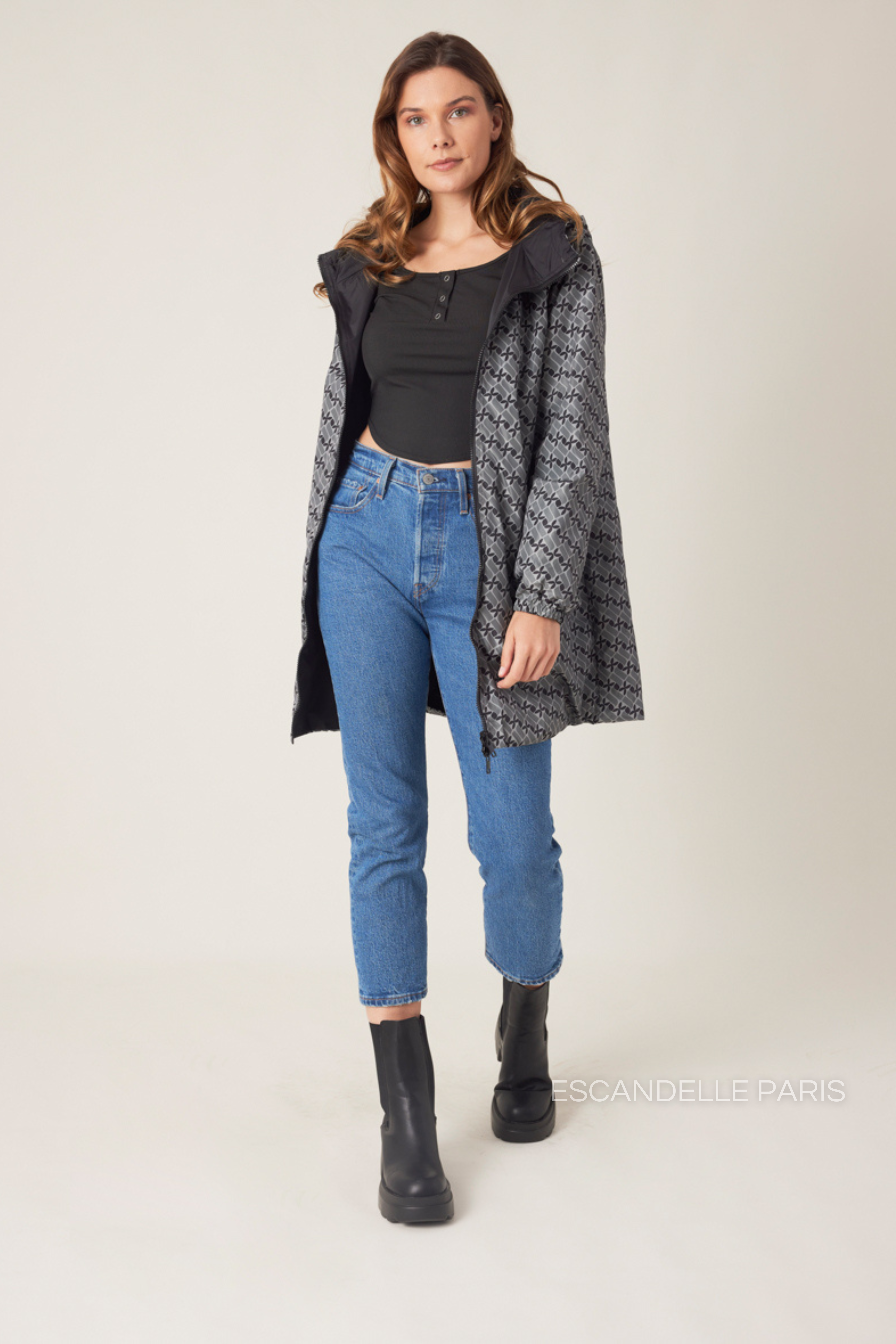 Femme portant la parka réversible LINA gris à motif géométrique, capuche dorée visible, vue de face
#couleur_gris