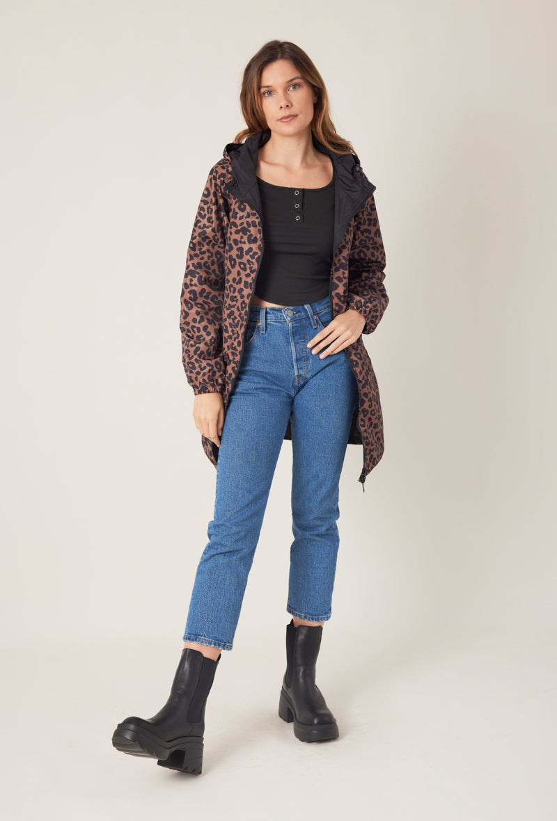 Femme portant la parka réversible JORDIE à motifs léopard noir et chocolat Escandelle Paris – look chic et confortable pour les jours de pluie - capuche et poches
#couleur_choco