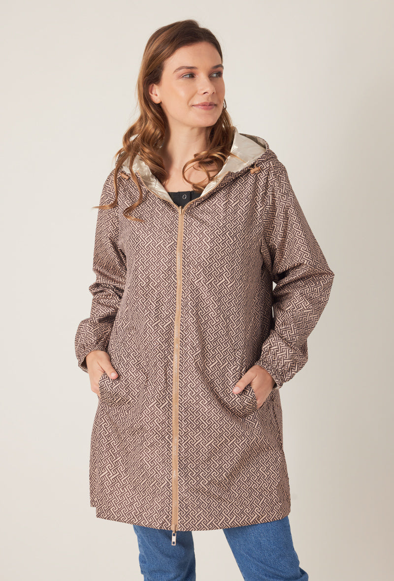 Femme portant la parka réversible LINA taupe à motif géométrique, capuche dorée visible, vue de face
#couleur_taupe