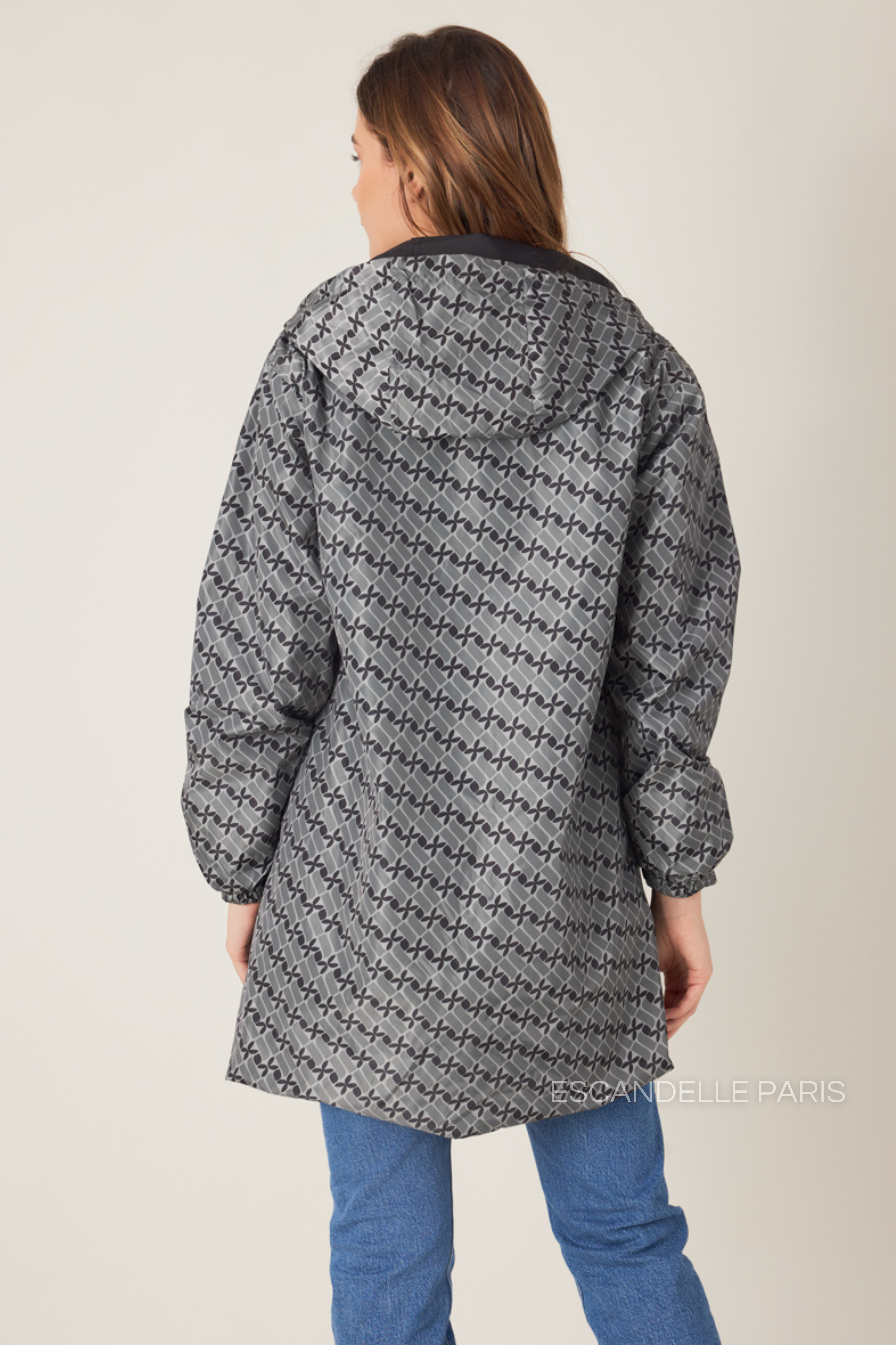 Femme portant la parka réversible LINA gris à motif géométrique, capuche dorée visible, vue de face
#couleur_gris