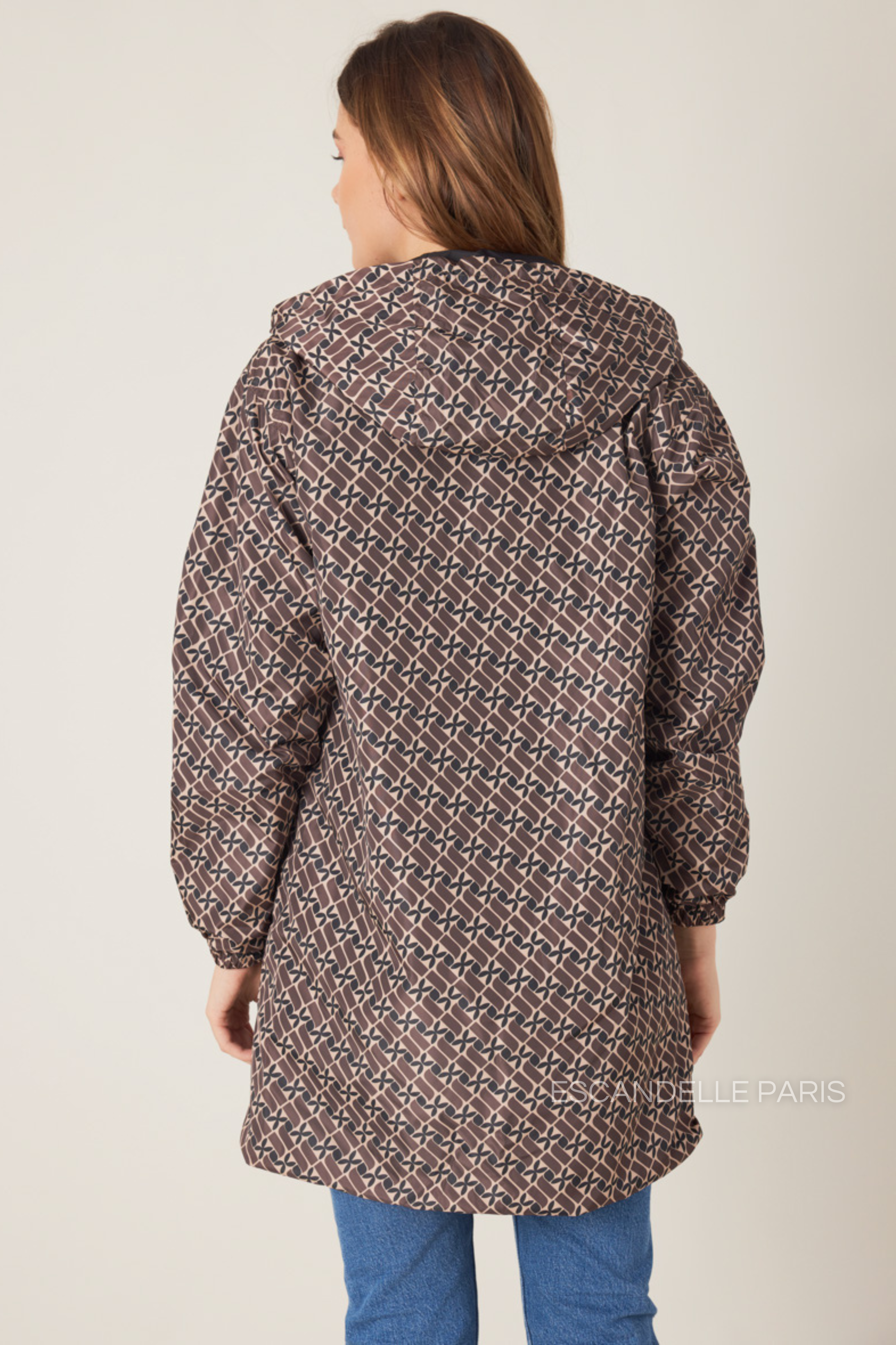 Femme portant la parka réversible LINA taupe à motif géométrique, capuche dorée visible, vue de face
#couleur_taupe