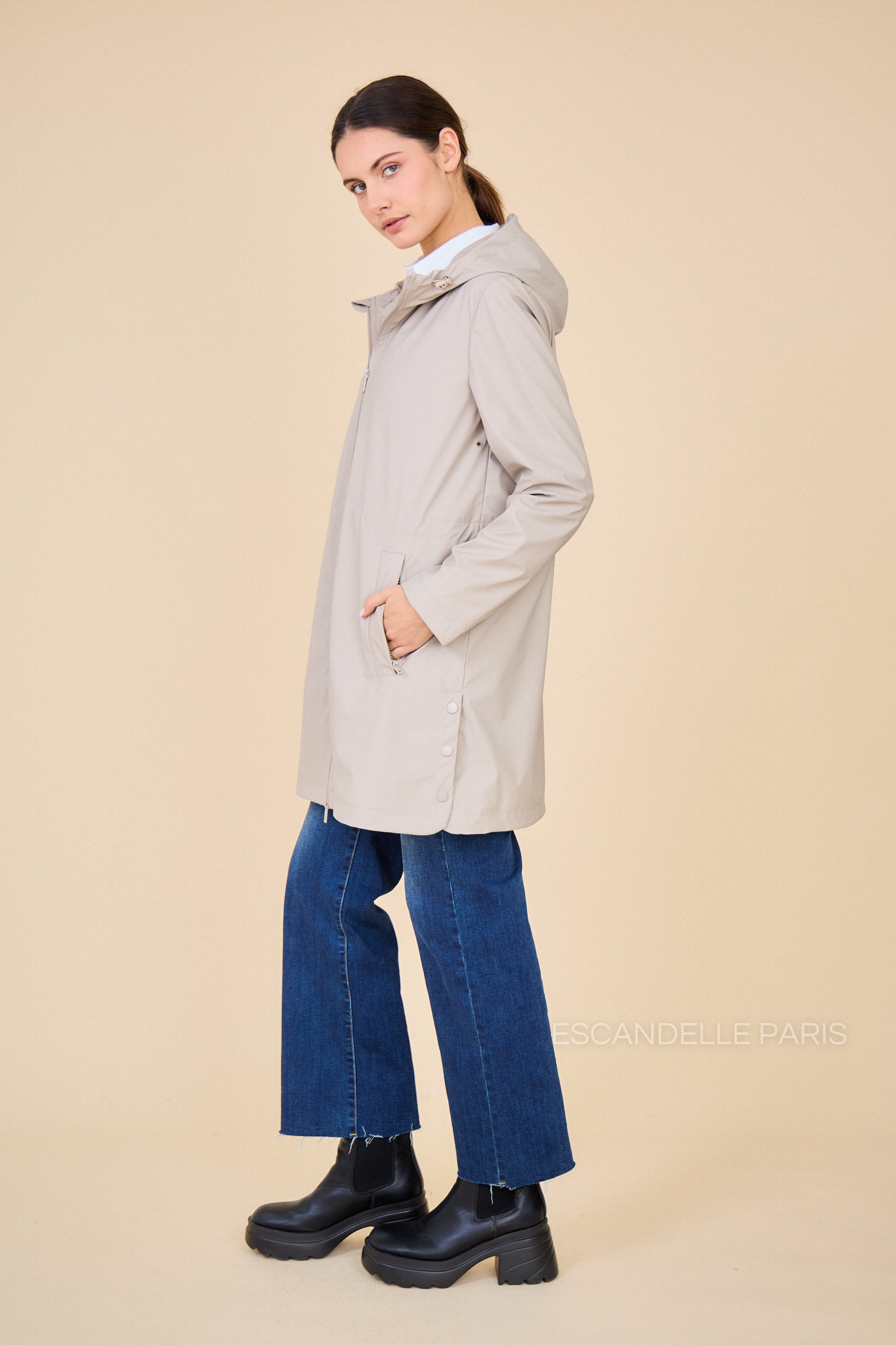 parka imperméable évasée avec élastique ajustable, côté. veste avec poches et capuche à cordon. Fente à boutons pressions sur les côtés #couleur_beige