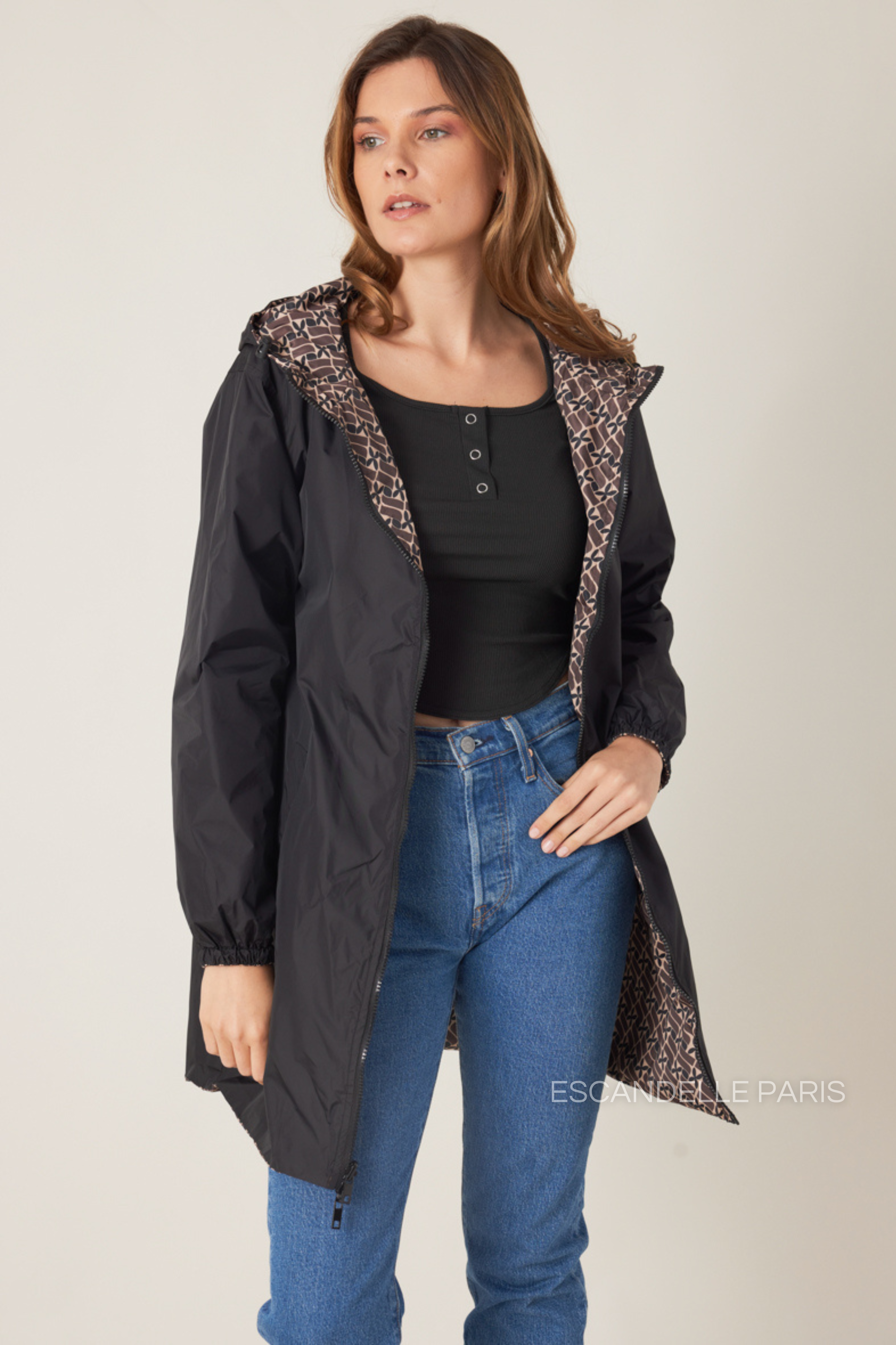 Femme portant la parka réversible LINA taupe à motif géométrique, capuche dorée visible, vue de face
#couleur_taupe