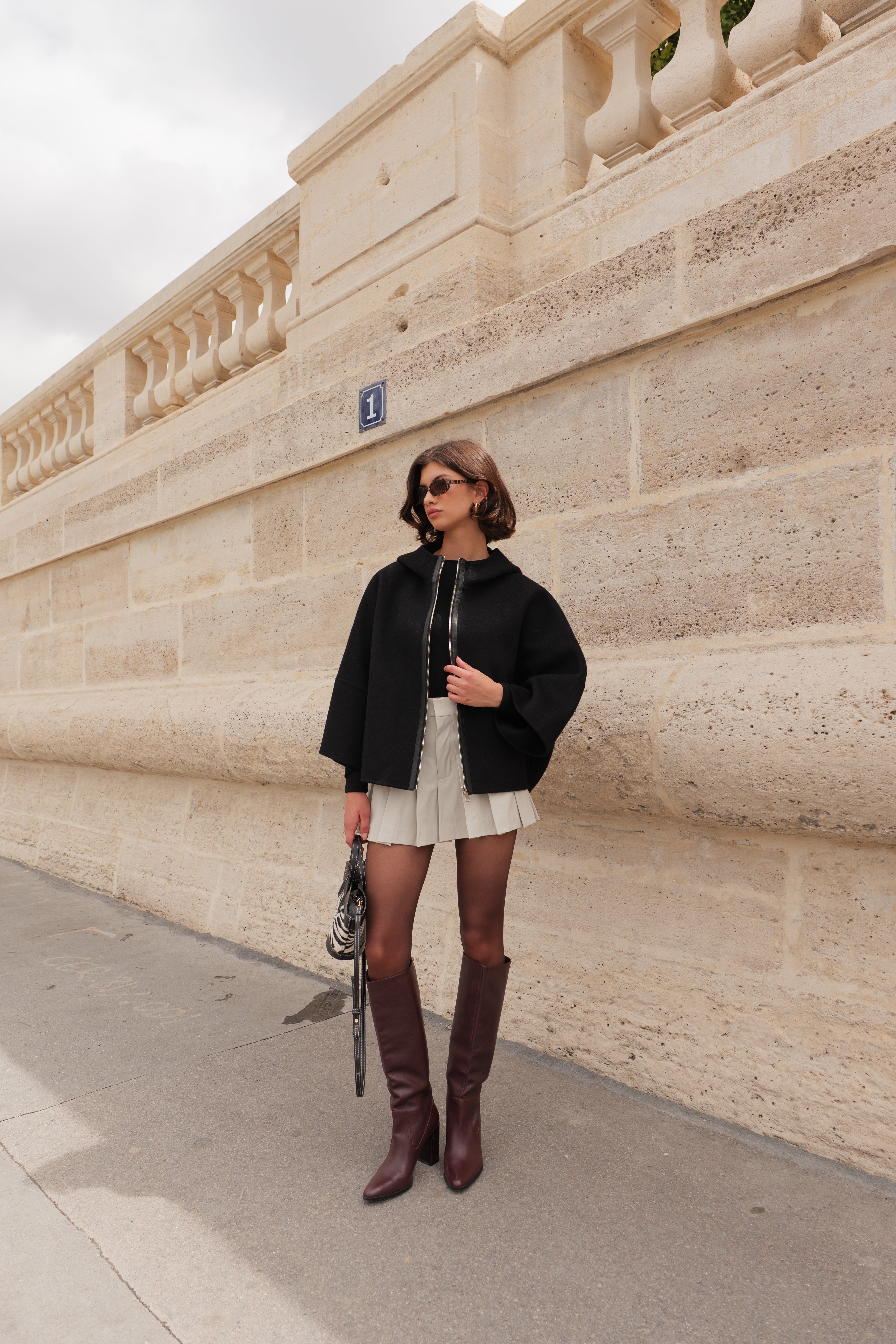 Cape ALAE Escandelle – cape en laine noire portée avec jupe plissée et accessoires modernes
#couleur_noir