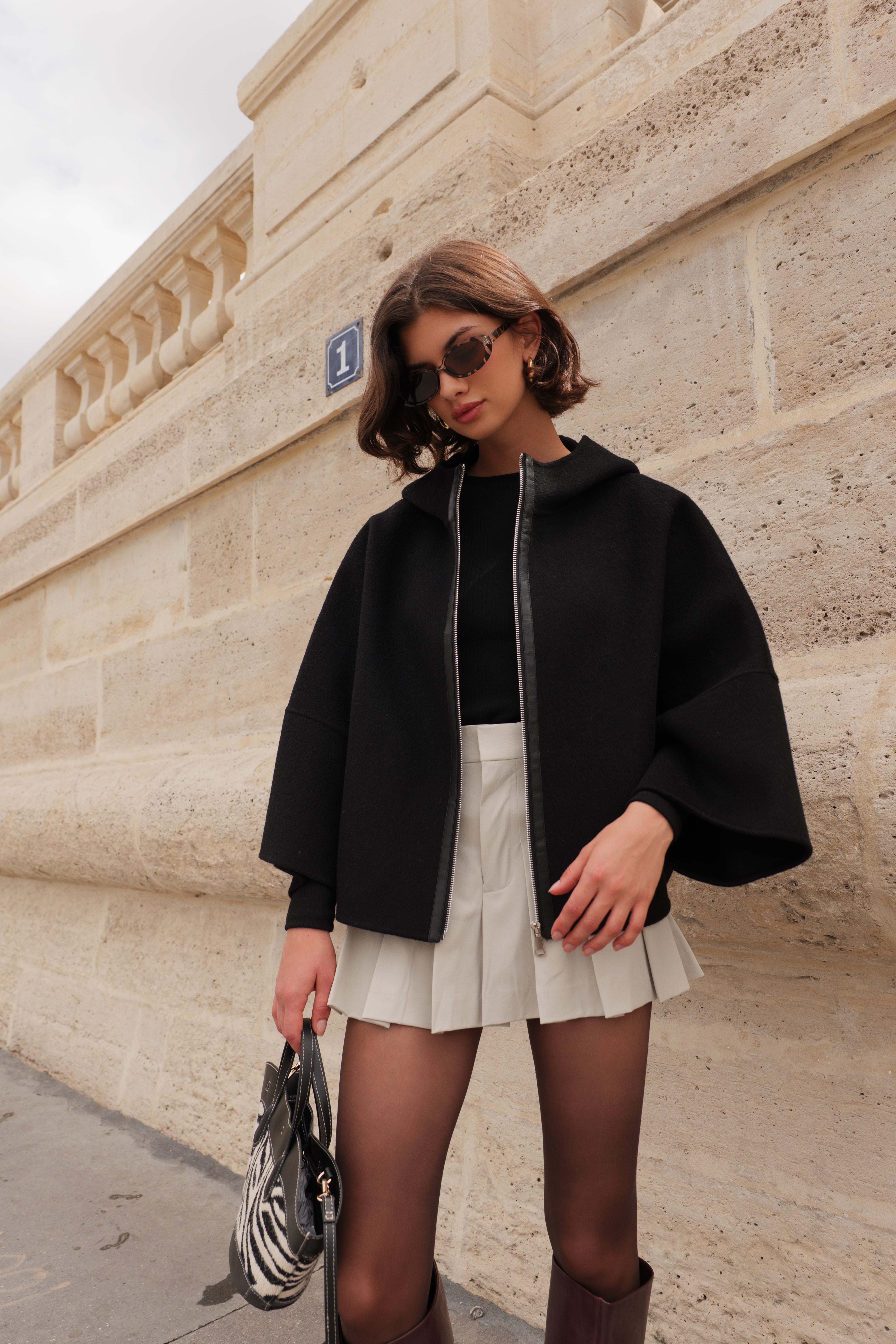 Cape ALAE Escandelle – cape en laine noire portée avec jupe plissée et accessoires modernes
#couleur_noir