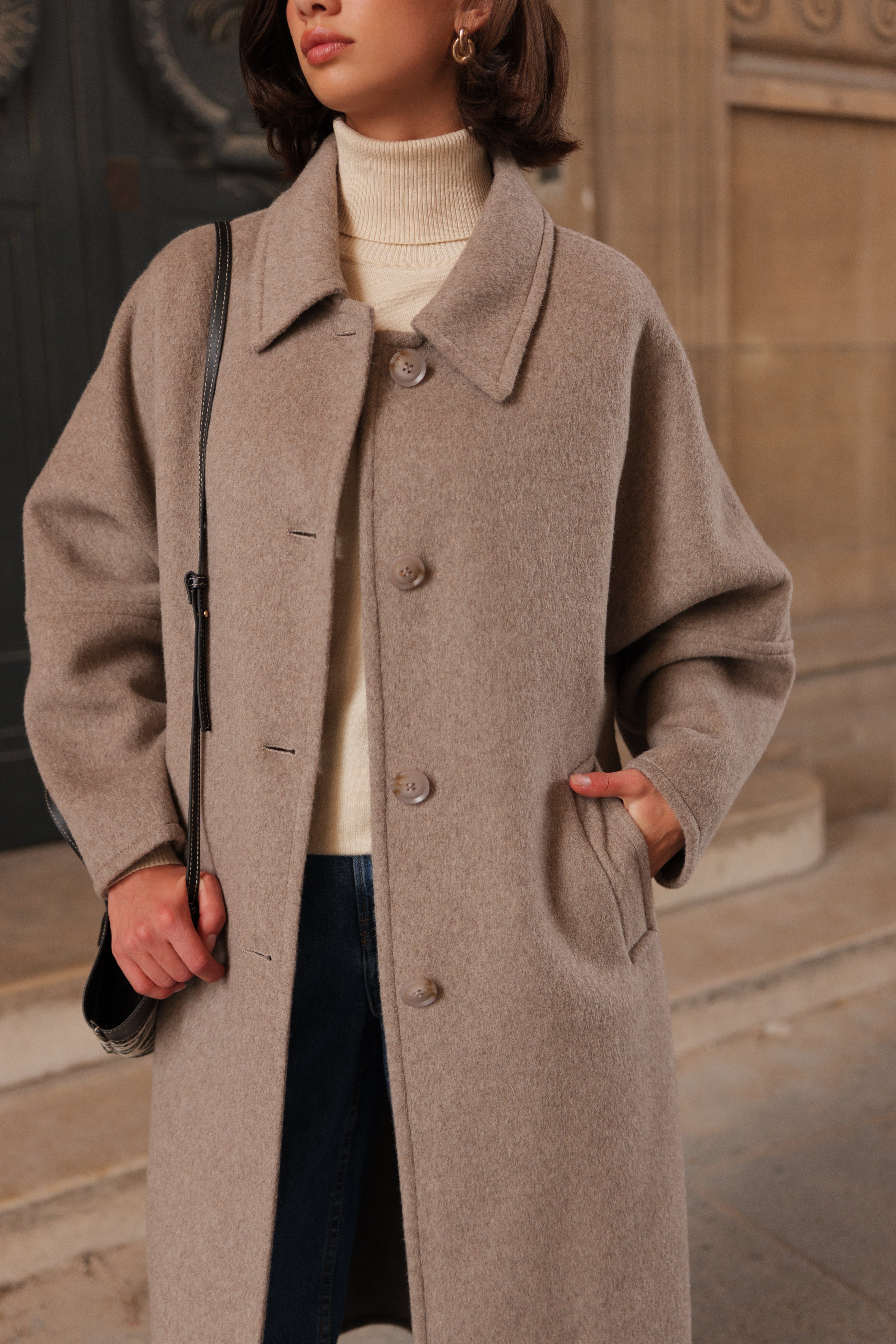 Manteau long femme en laine beige CELESTE, coupe droite et ample, col chemise et poches latérales, porté avec un pull écru et un pantalon en jean.
#couleur_beige