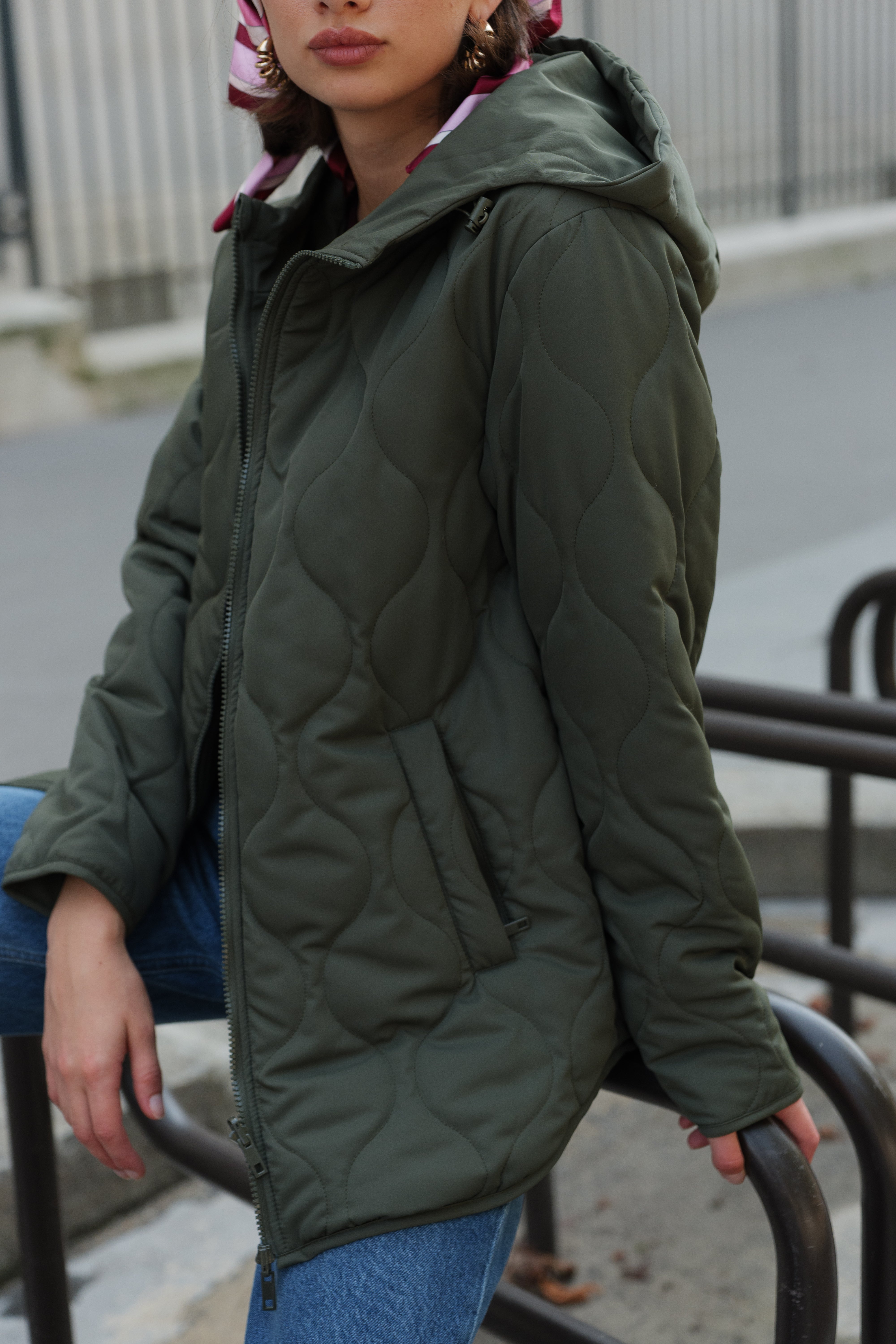 Veste matelassée kaki CASSIS Escandelle – look parisien moderne avec jean, foulard et boucles dorées.
#couleur_kaki