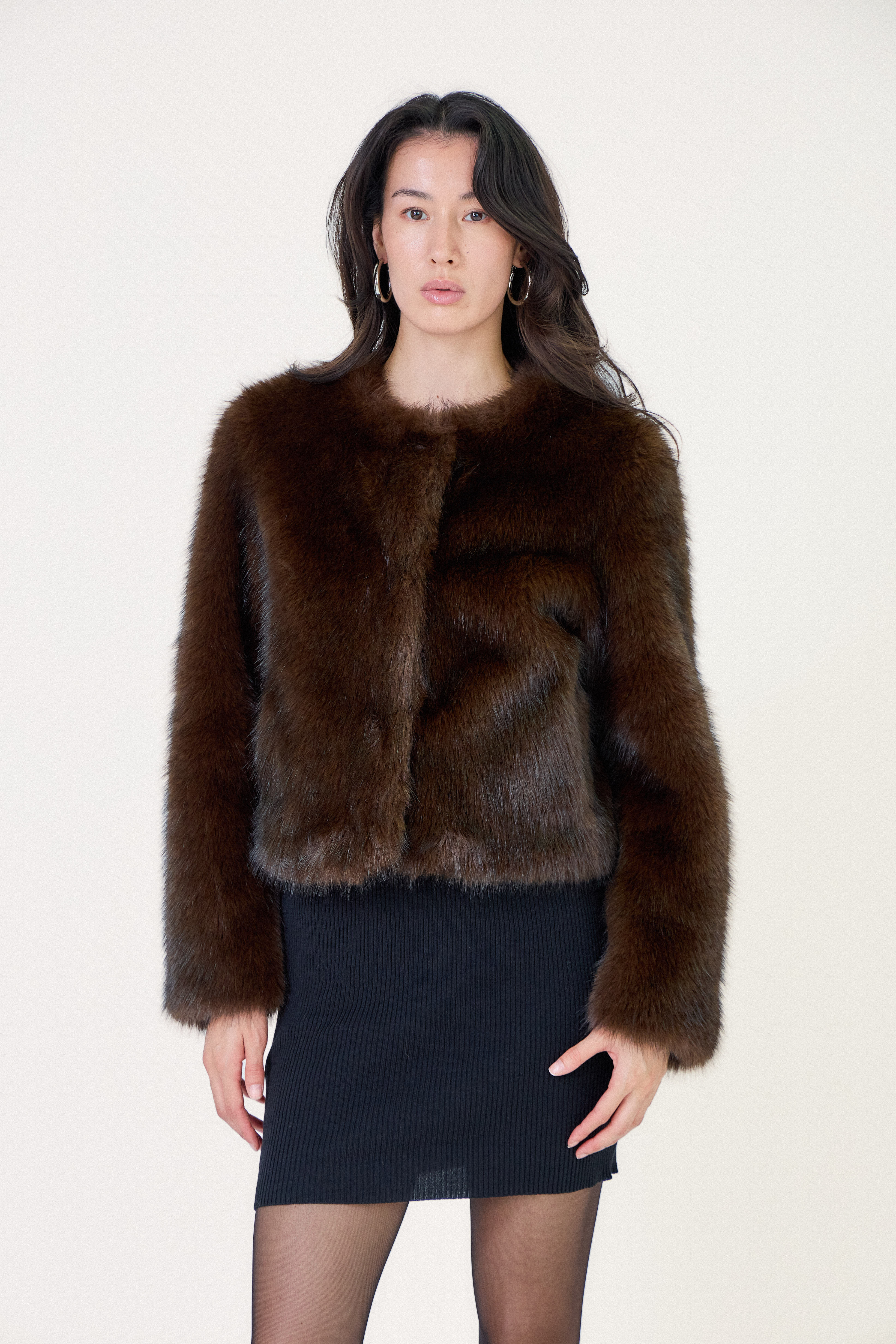 Manteau court en fausse fourrure femme Escandelle Paris, coloris choco, col rond, fermeture à pressions dissimulées, coupe élégante et poils longs doux.
#couleur_choco