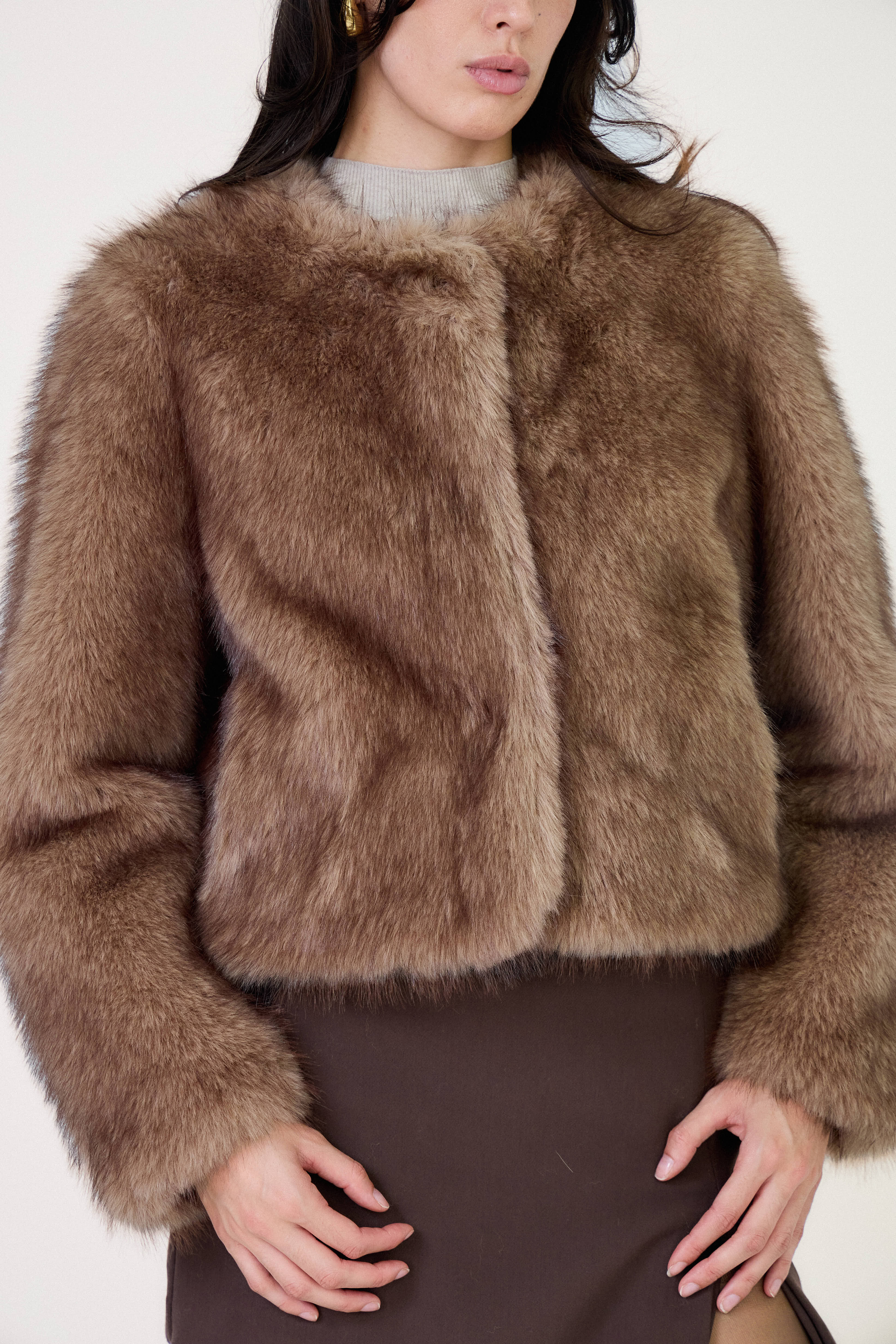 Manteau court en fausse fourrure femme Escandelle Paris, coloris brun, col rond, fermeture à pressions dissimulées, coupe élégante et poils longs doux.
#couleur_taupe