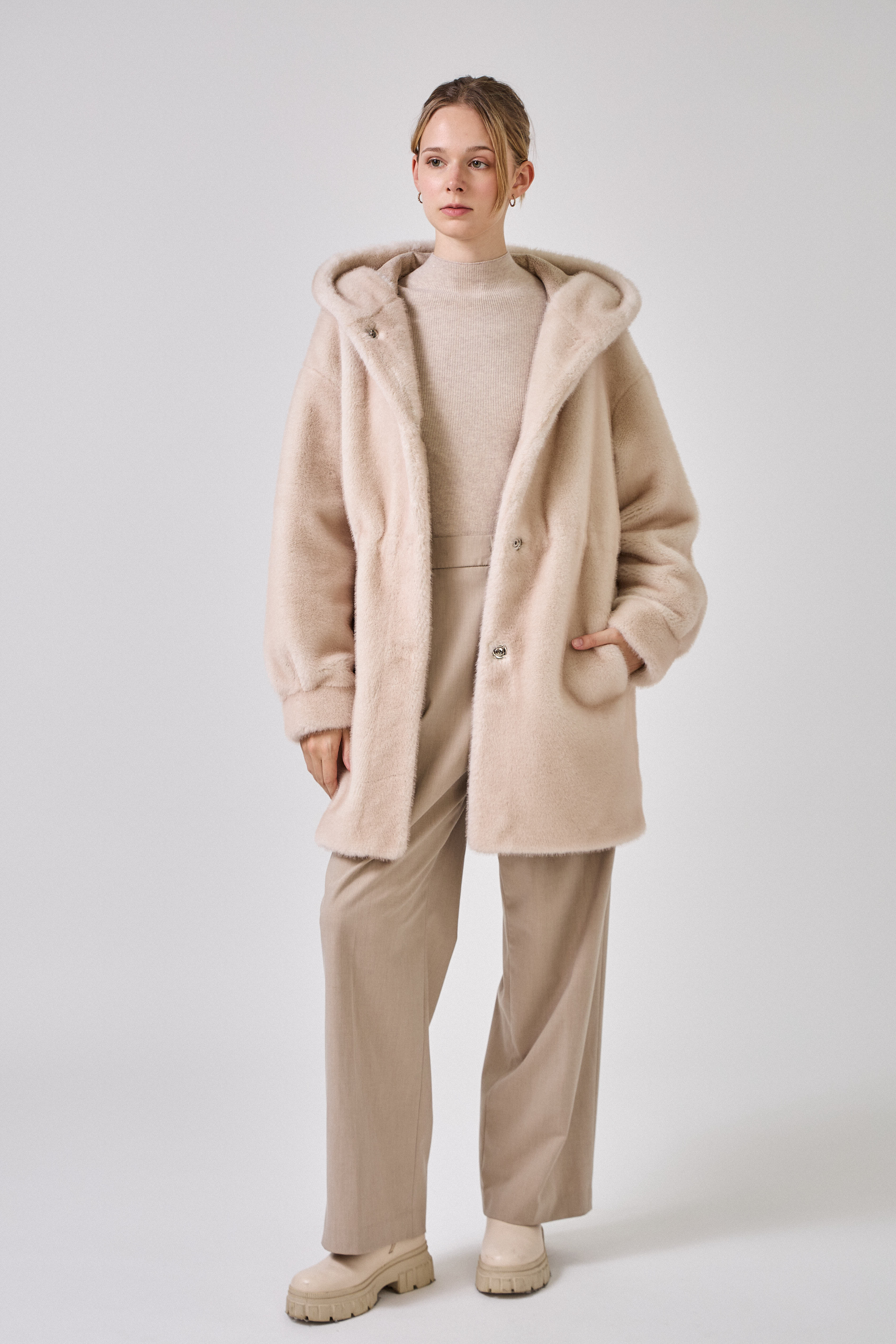 Femme portant le manteau long GRACE en fausse fourrure choco, coupe droite et capuche
#couleur_écru