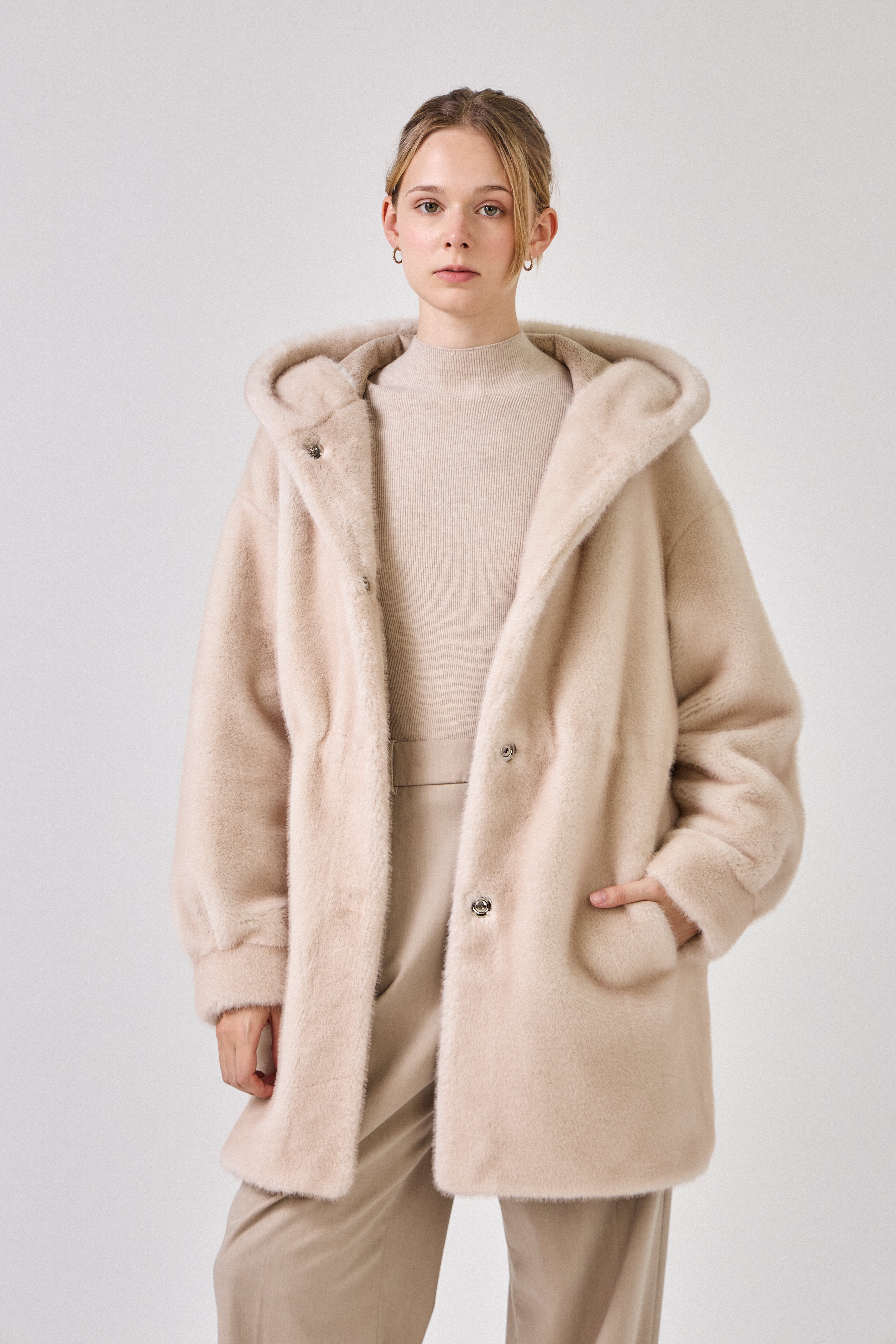 Femme portant le manteau long GRACE en fausse fourrure choco, coupe droite et capuche
#couleur_écru