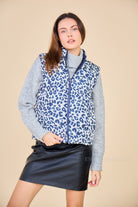 doudoune sans manches Luna, couleur marine à motifs léopard. Veste réversible. Look Escandelle Paris avec jupe en similicuir et pull gris col roulé