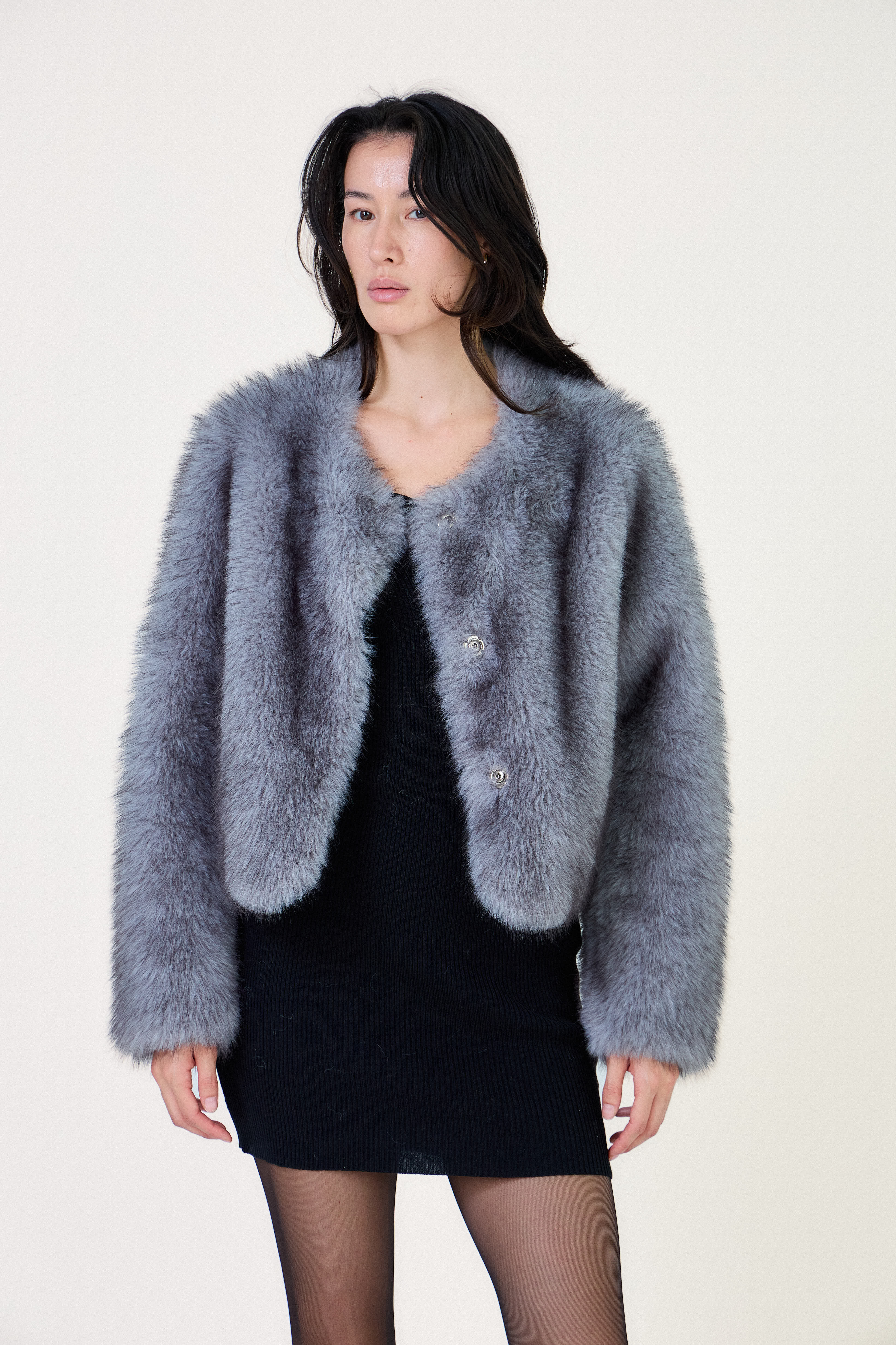 Manteau court en fausse fourrure femme Escandelle Paris, coloris gris, col rond, fermeture à pressions dissimulées, coupe élégante et poils longs doux.
#couleur_gris