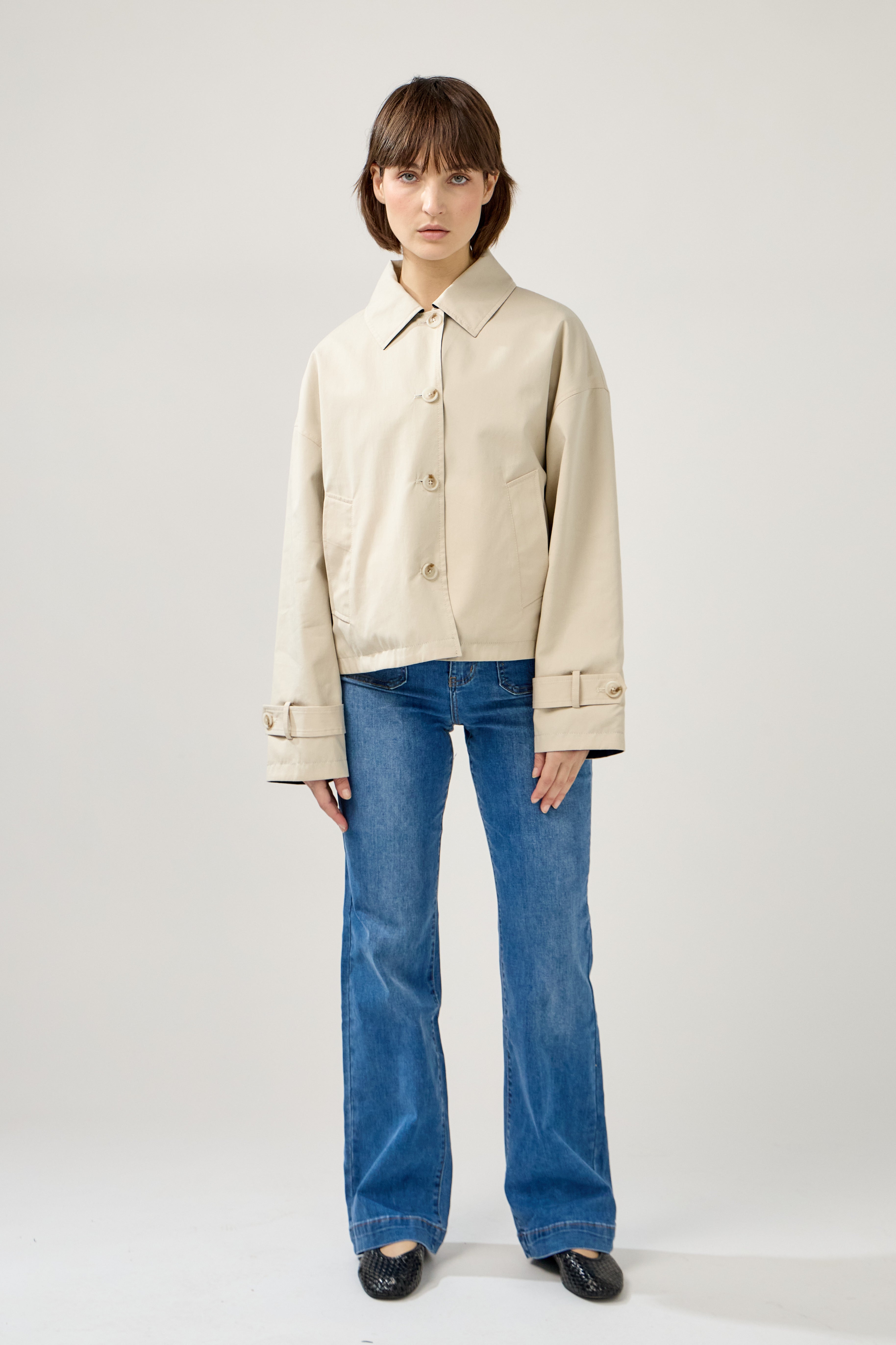 femme portant un veste style trench réversible imperméable, fermeture à boutons, poches et col français, devant
#couleur_beige