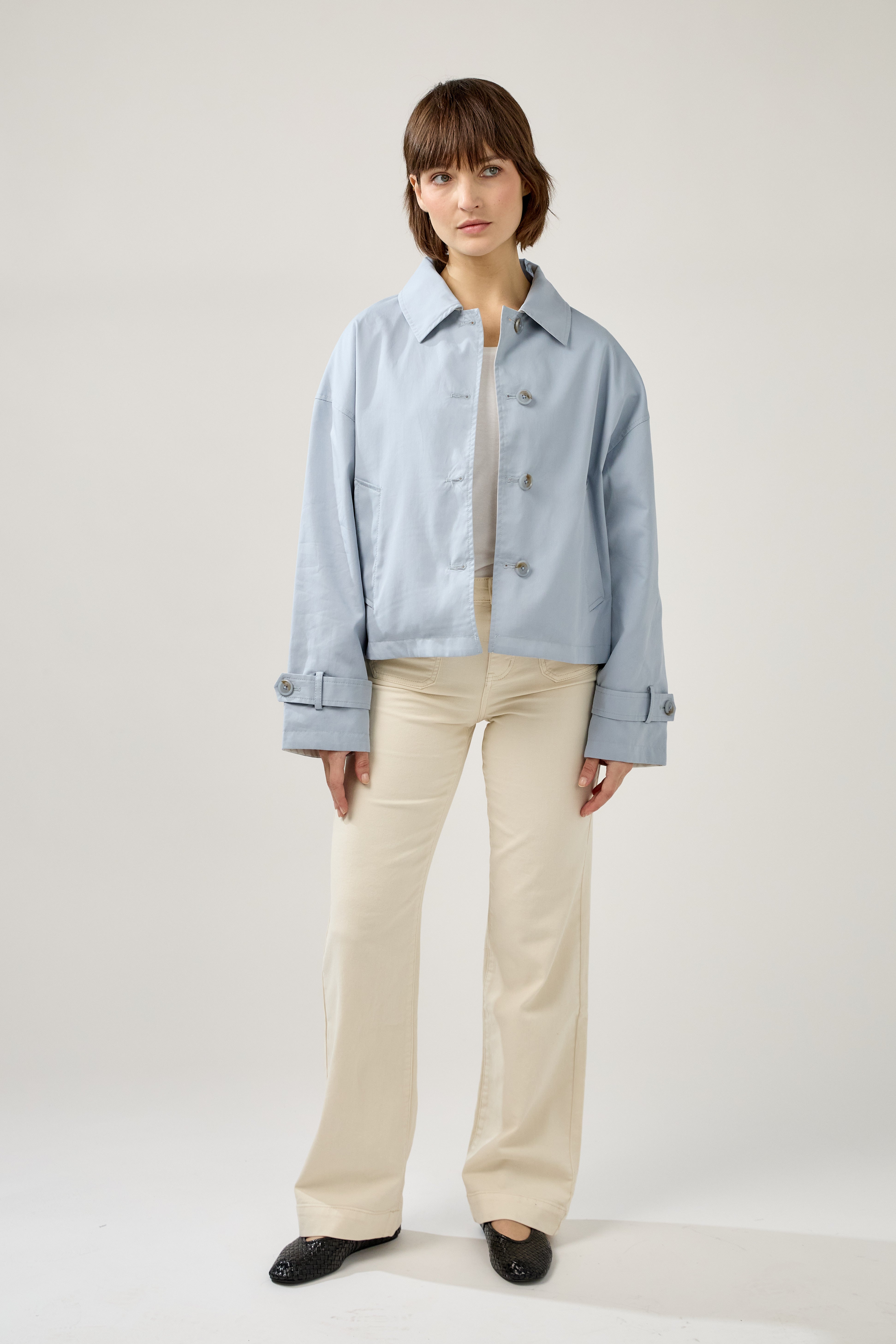 femme portant un veste style trench réversible imperméable, fermeture à boutons, poches et col français, devant
#couleur_ciel