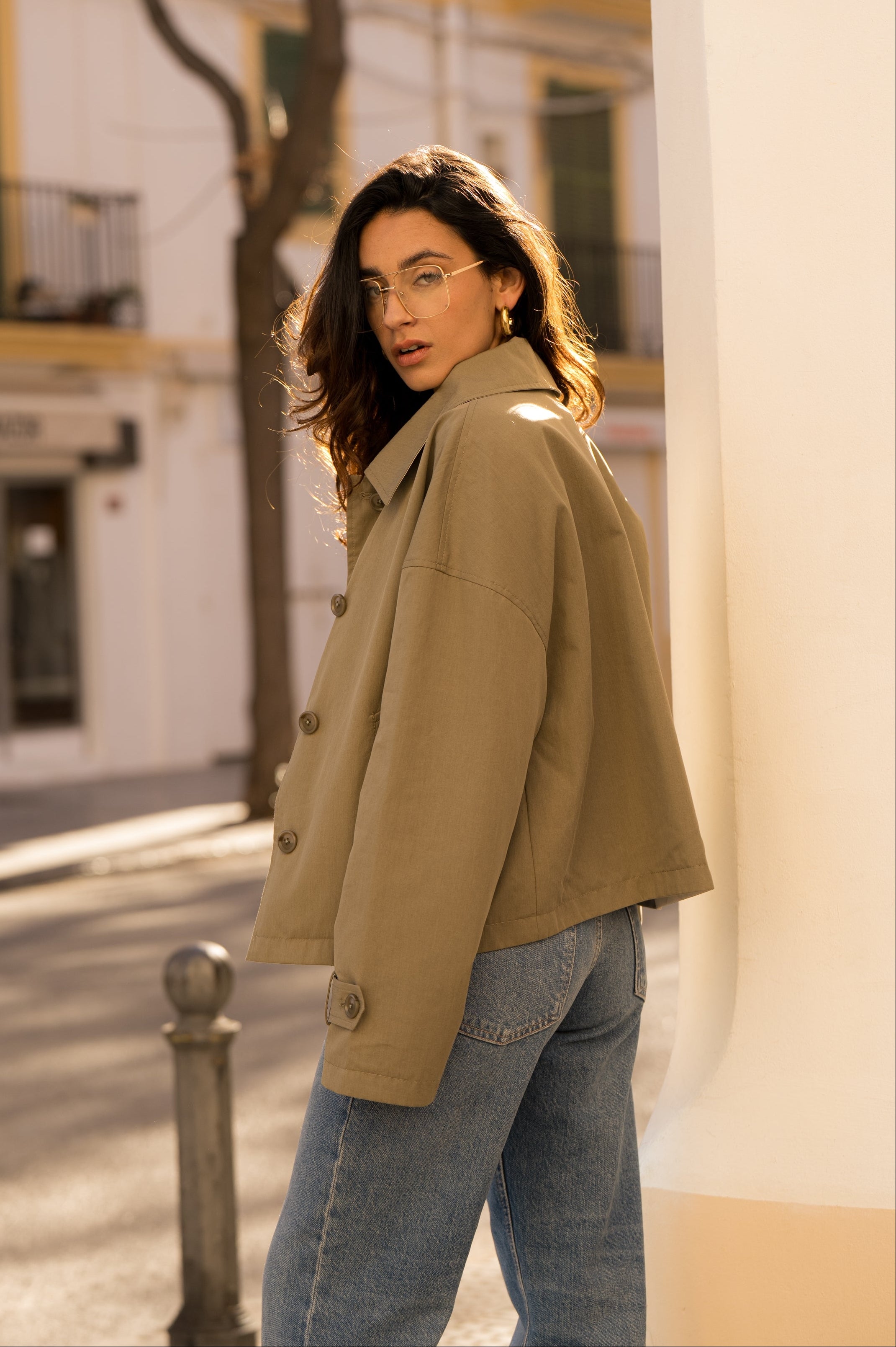 femme portant un veste style trench réversible imperméable, fermeture à boutons, poches et col français, côté
#couleur_kaki