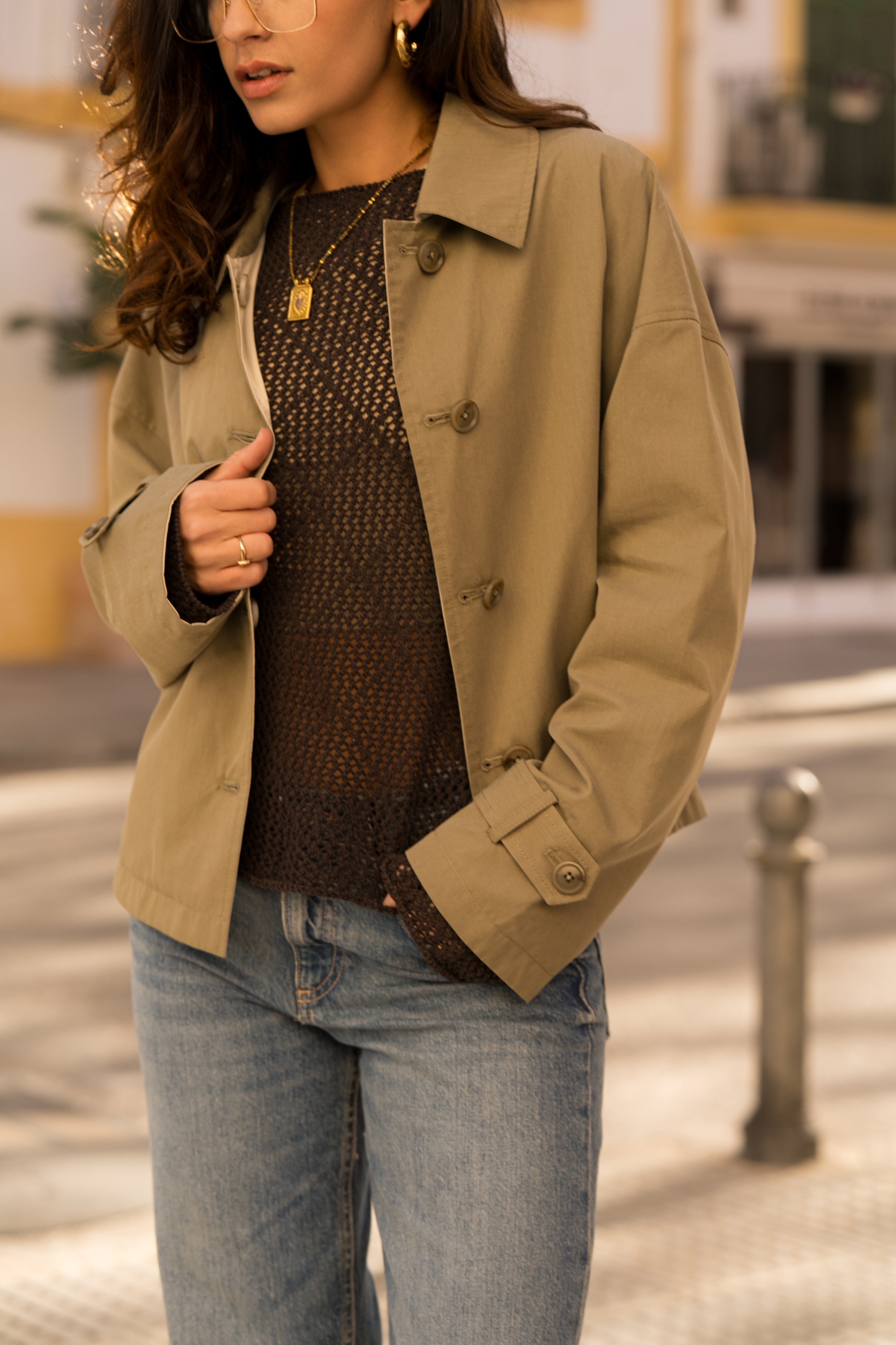 femme portant un veste style trench réversible imperméable, fermeture à boutons, poches et col français, zoom devant
#couleur_kaki