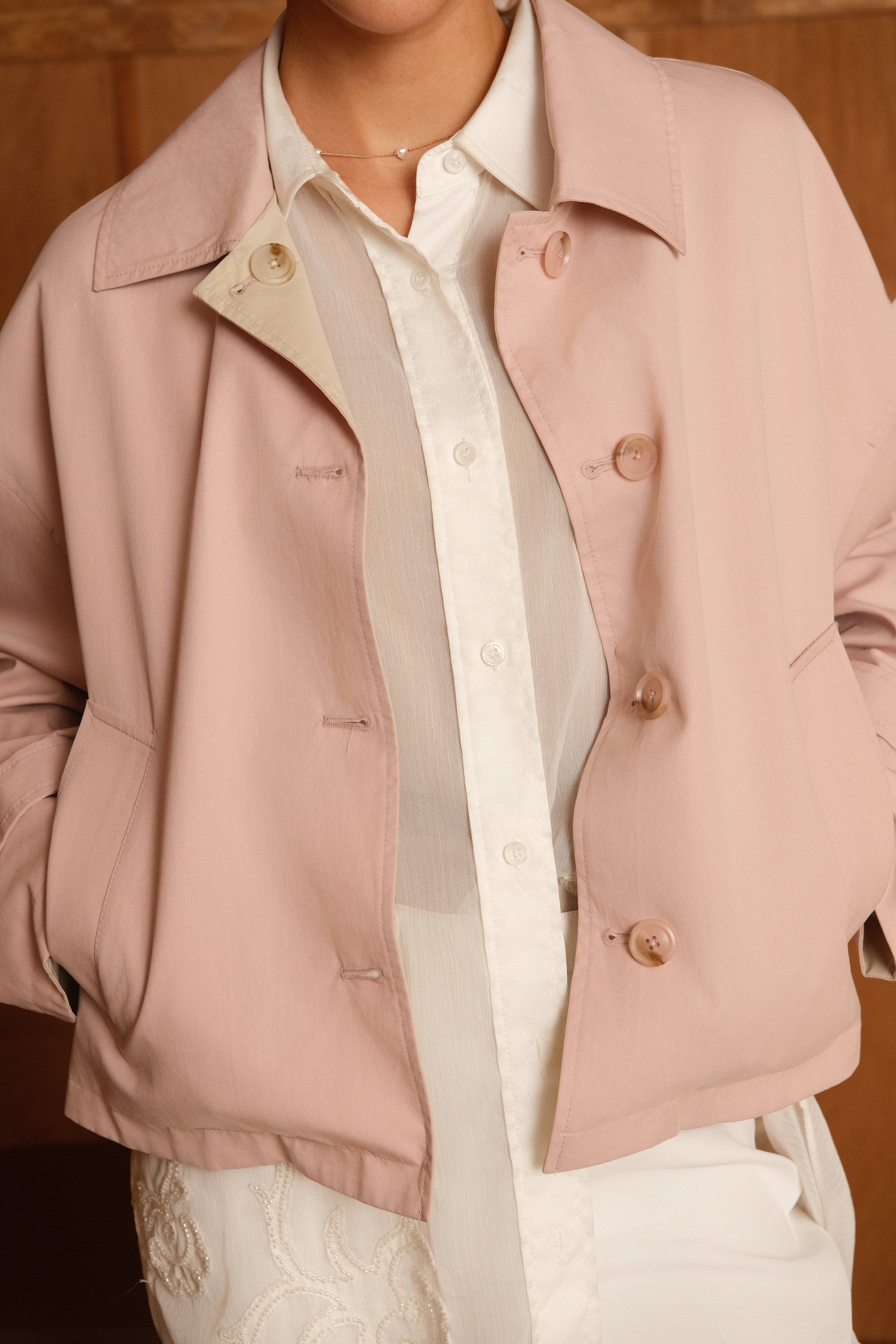 femme portant un veste style trench réversible imperméable, fermeture à boutons, poches et col français, zoom devant
#couleur_rose