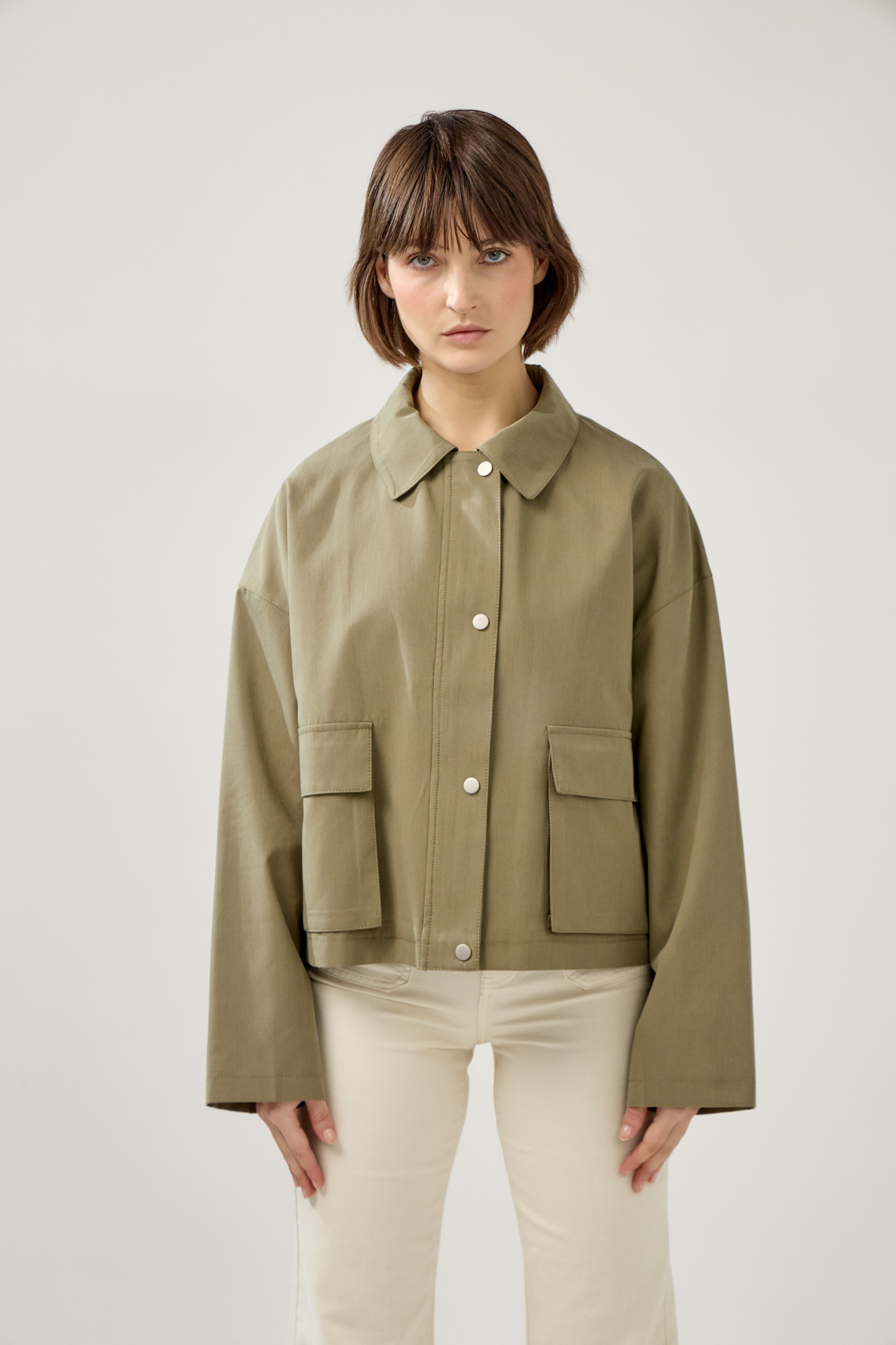 veste en coton kaki clair courte et droite, fermeture à glissière métallique et boutonnière pressions, poches cargos et col français, devant
#couleur_kaki