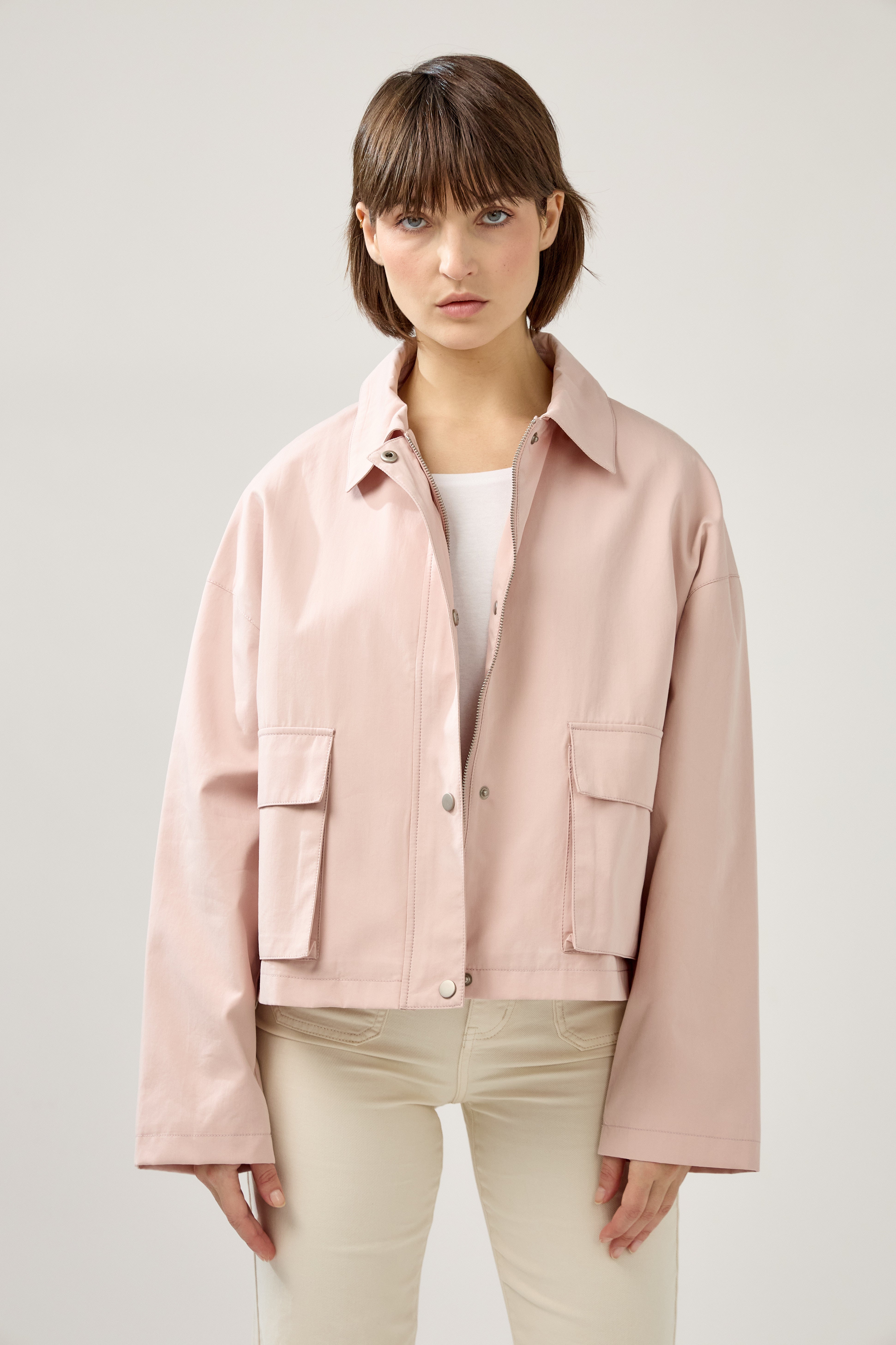 veste en coton rose pâle courte et droite, fermeture à glissière métallique et boutonnière pressions, poches cargos et col français, devant
#couleur_rose