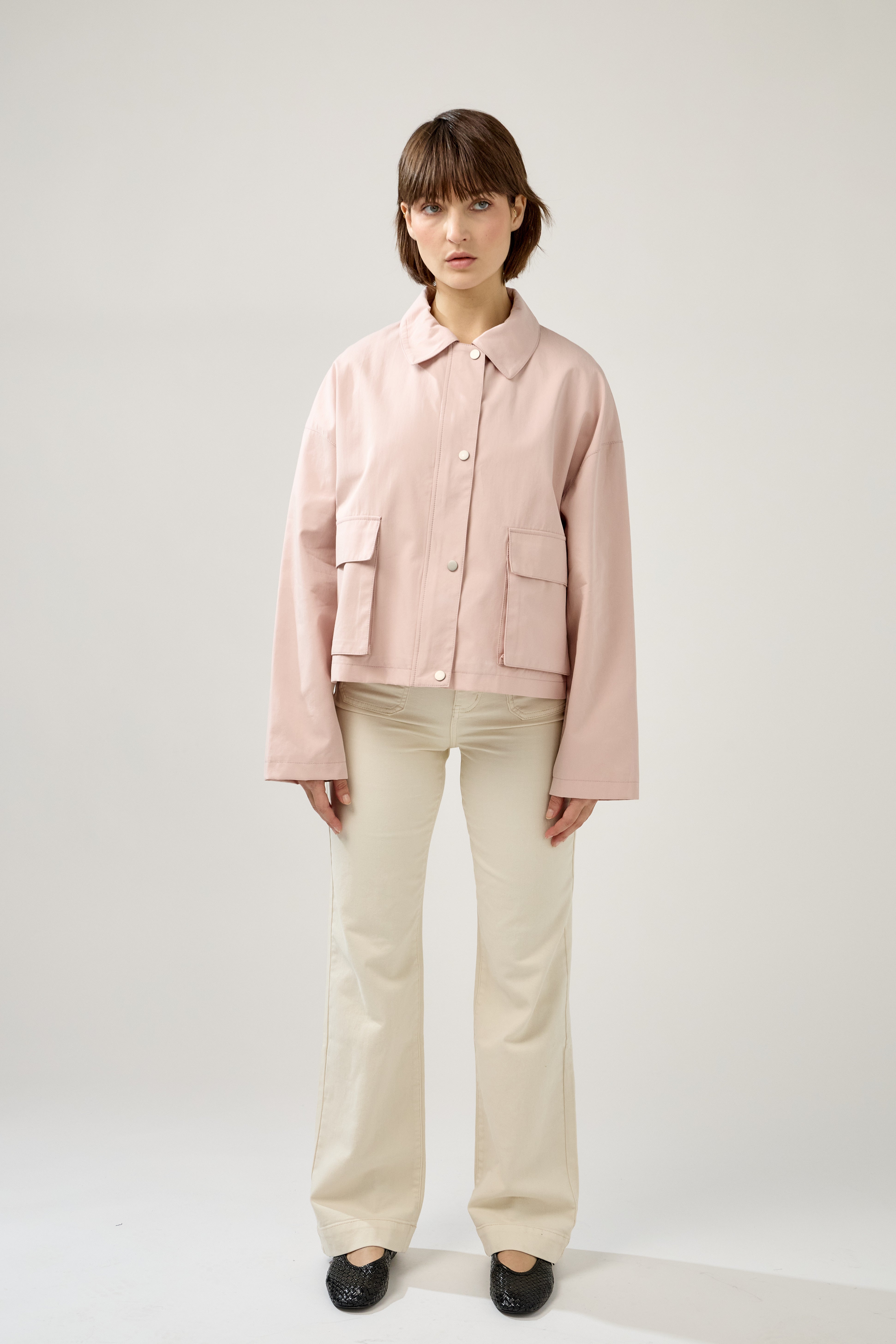 veste en coton rose pâle courte et droite, fermeture à glissière métallique et boutonnière pressions, poches cargos et col français, devant
#couleur_rose