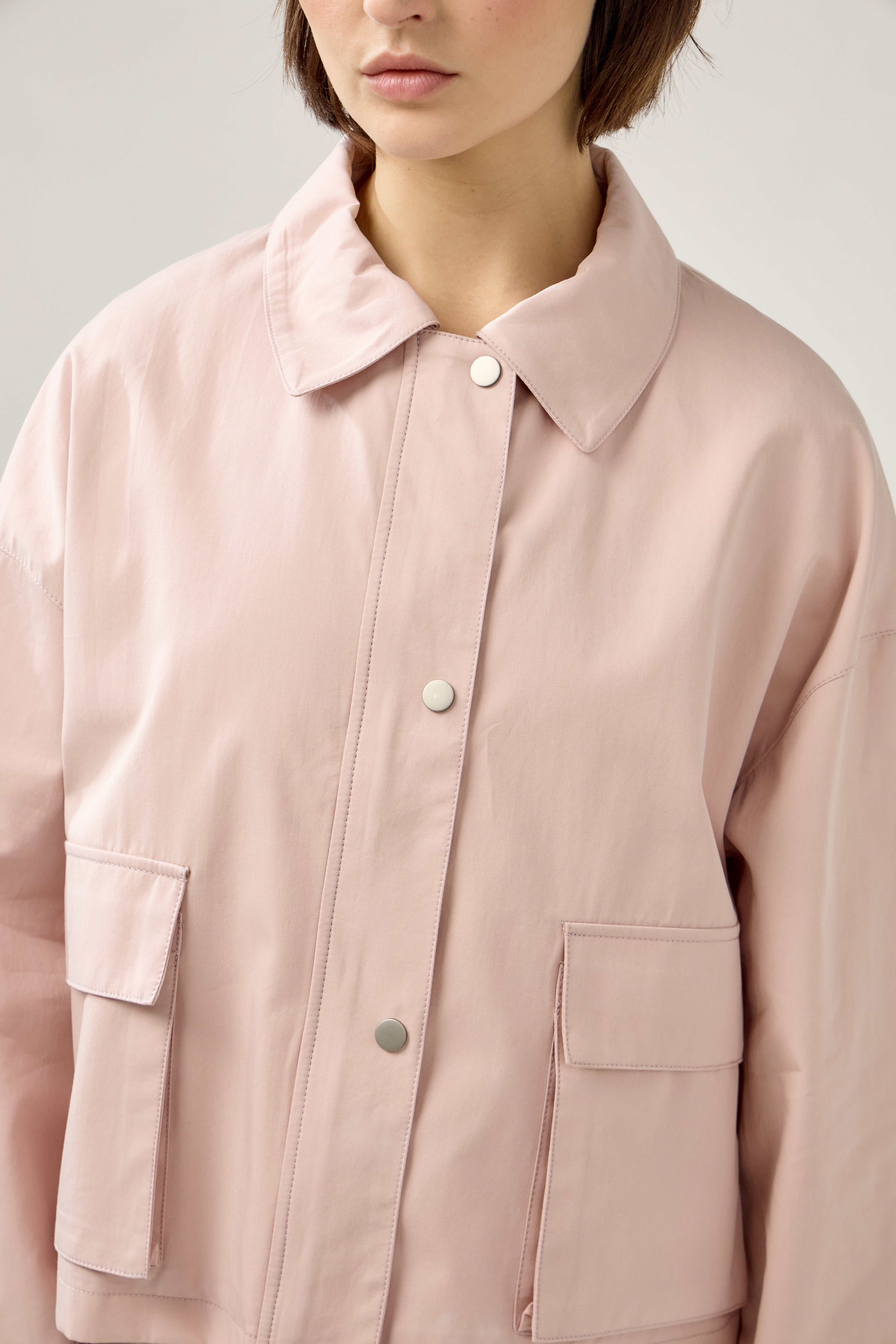 veste en coton rose pâle courte et droite, fermeture à glissière métallique et boutonnière pressions, poches cargos et col français, zoom devant
#couleur_rose