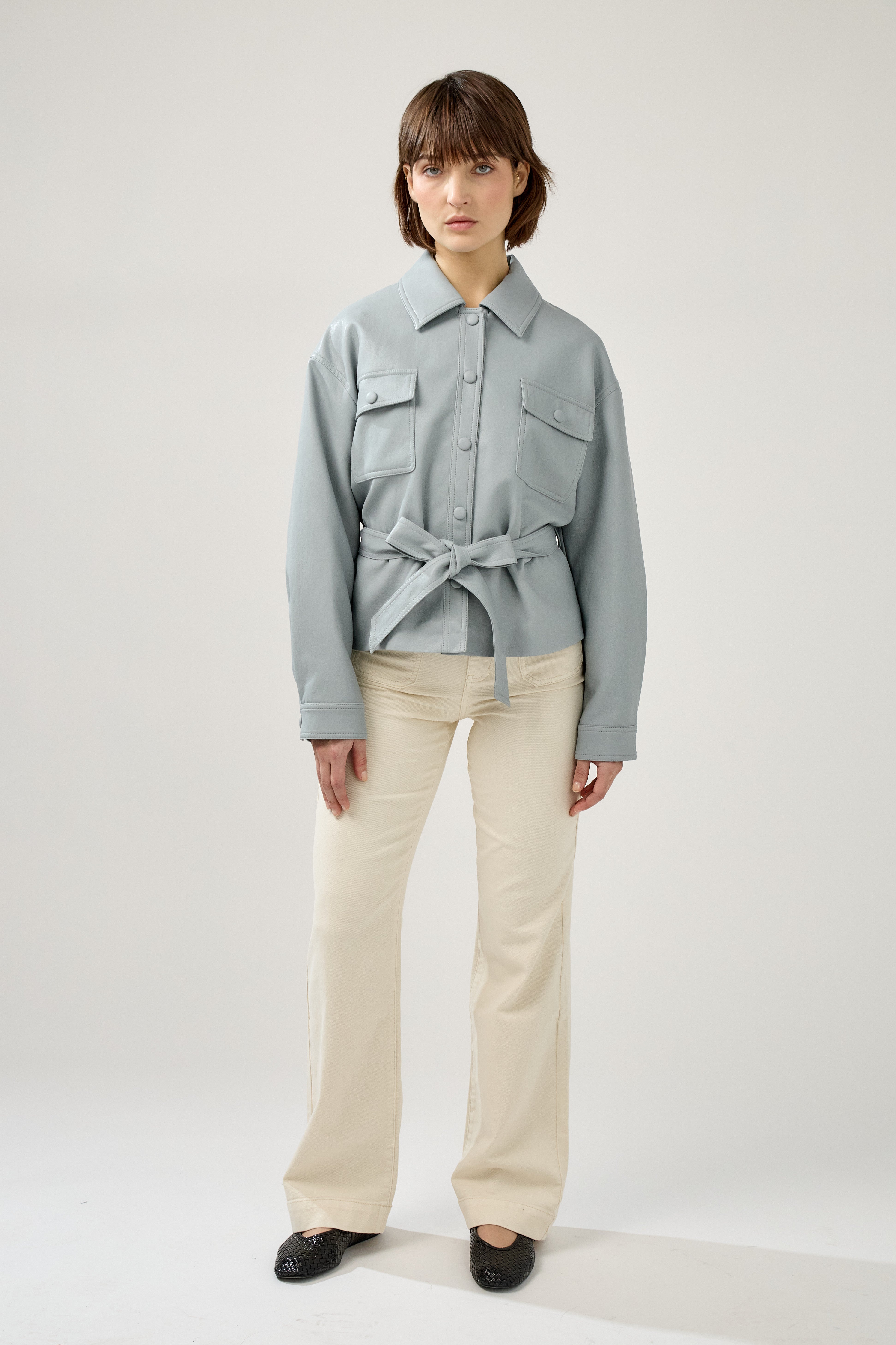 veste en similicuir à ceinture, col français, poches plaquées à rabats boutonnées poitrine, boutonnière avant boutons pressions, devant
#couleur_ciel