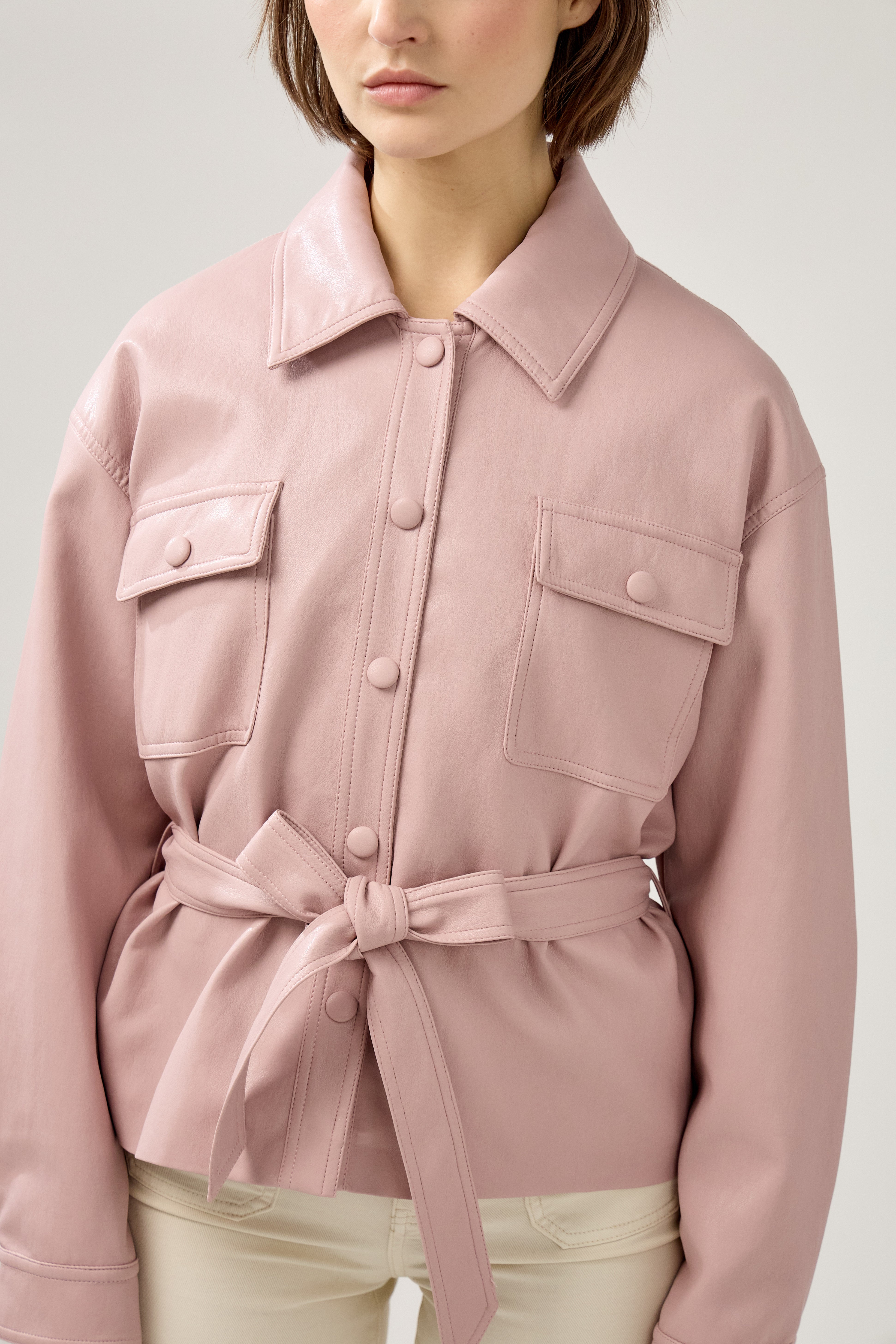 veste en similicuir à ceinture, col français, poches plaquées à rabats boutonnées poitrine, boutonnière avant boutons pressions, devant
#couleur_rose