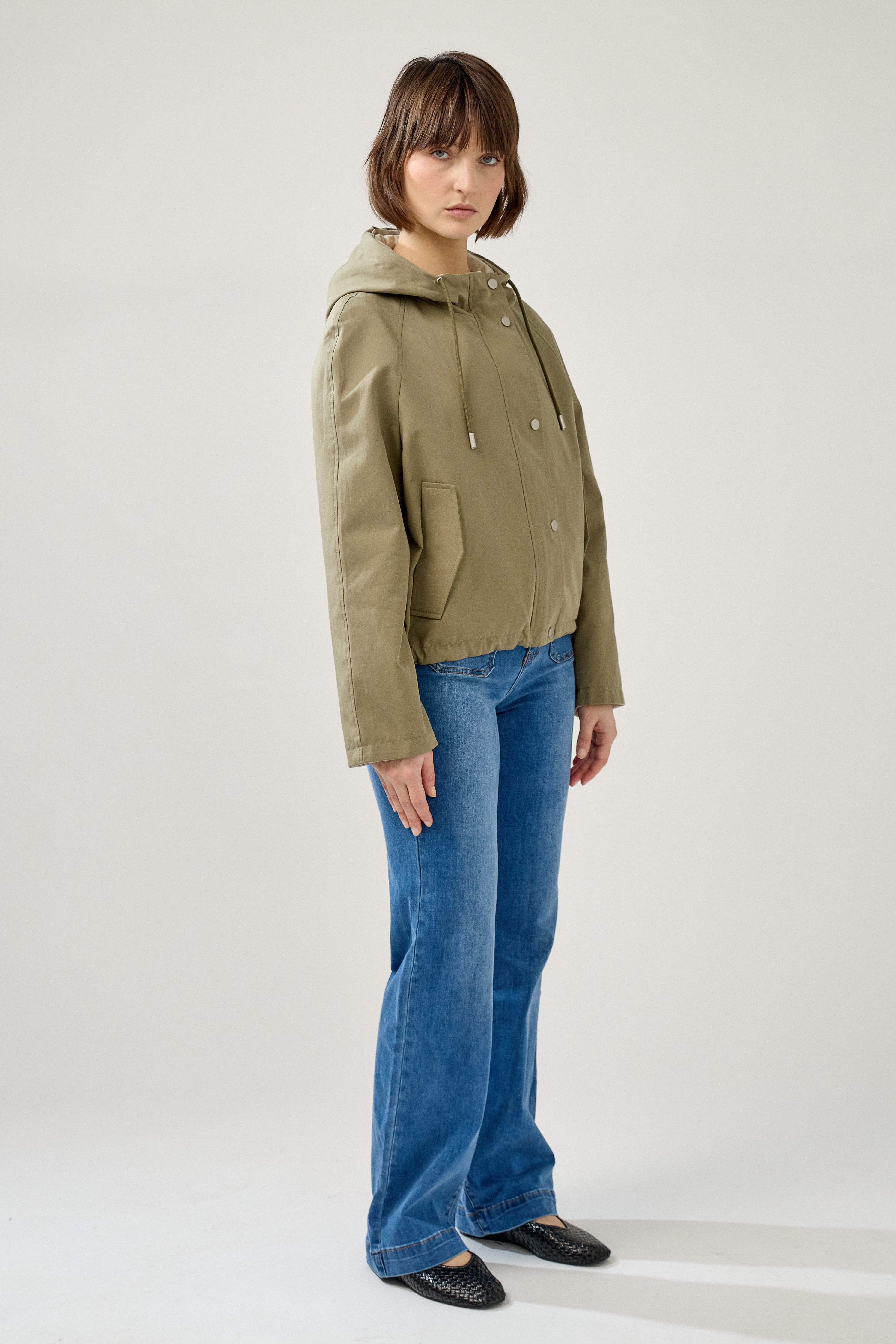 femme portant la parka Elunia réversible kaki clair/beige, fermeture à glissière et boutons à pressions, capuche à cordon, poche à rabats, bas ajustable, côté
#couleur_kaki