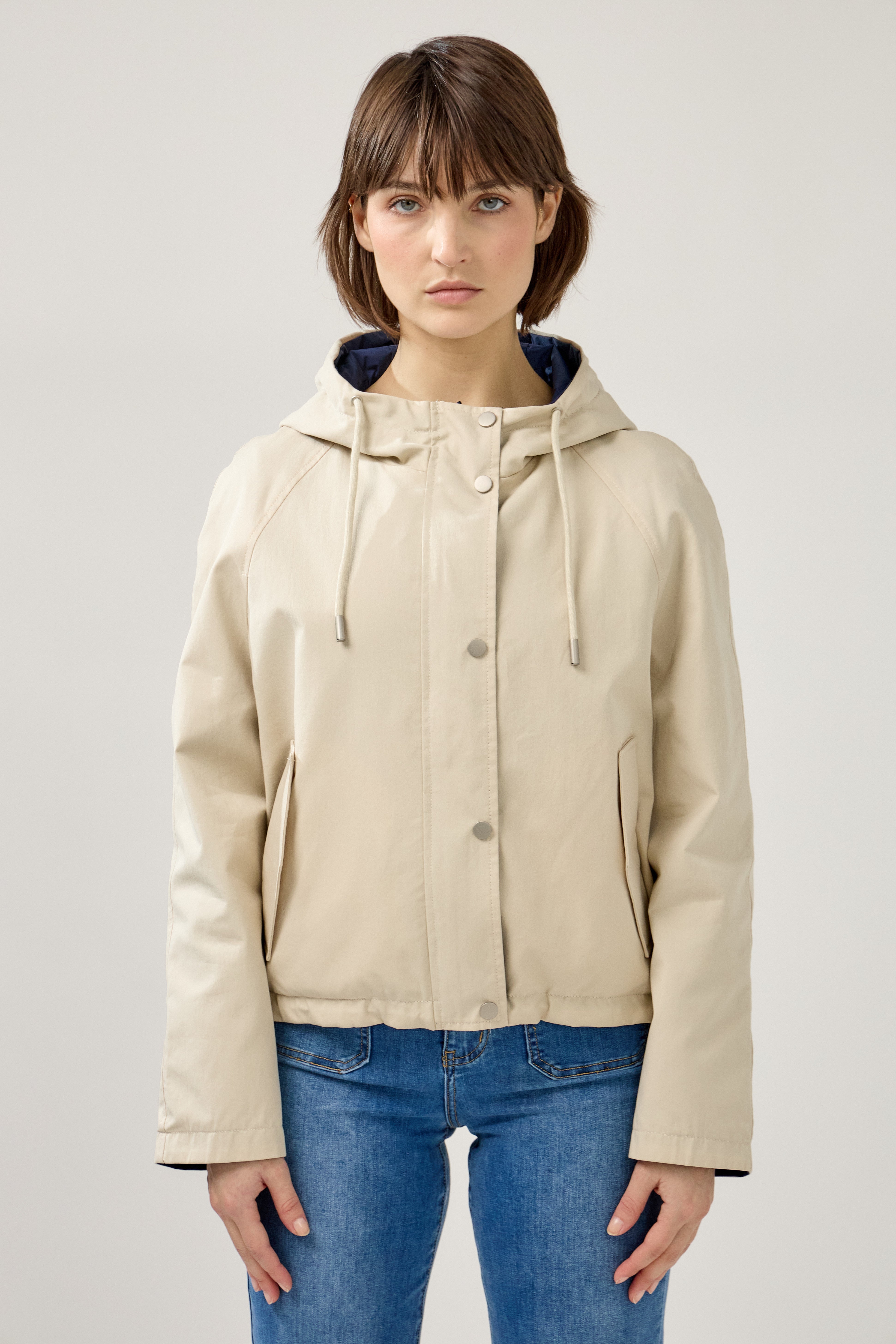 femme portant la parka Elunia réversible beige/marine, fermeture à glissière et boutons à pressions, capuche à cordon, poche à rabats, bas ajustable, devant
#couleur_beige