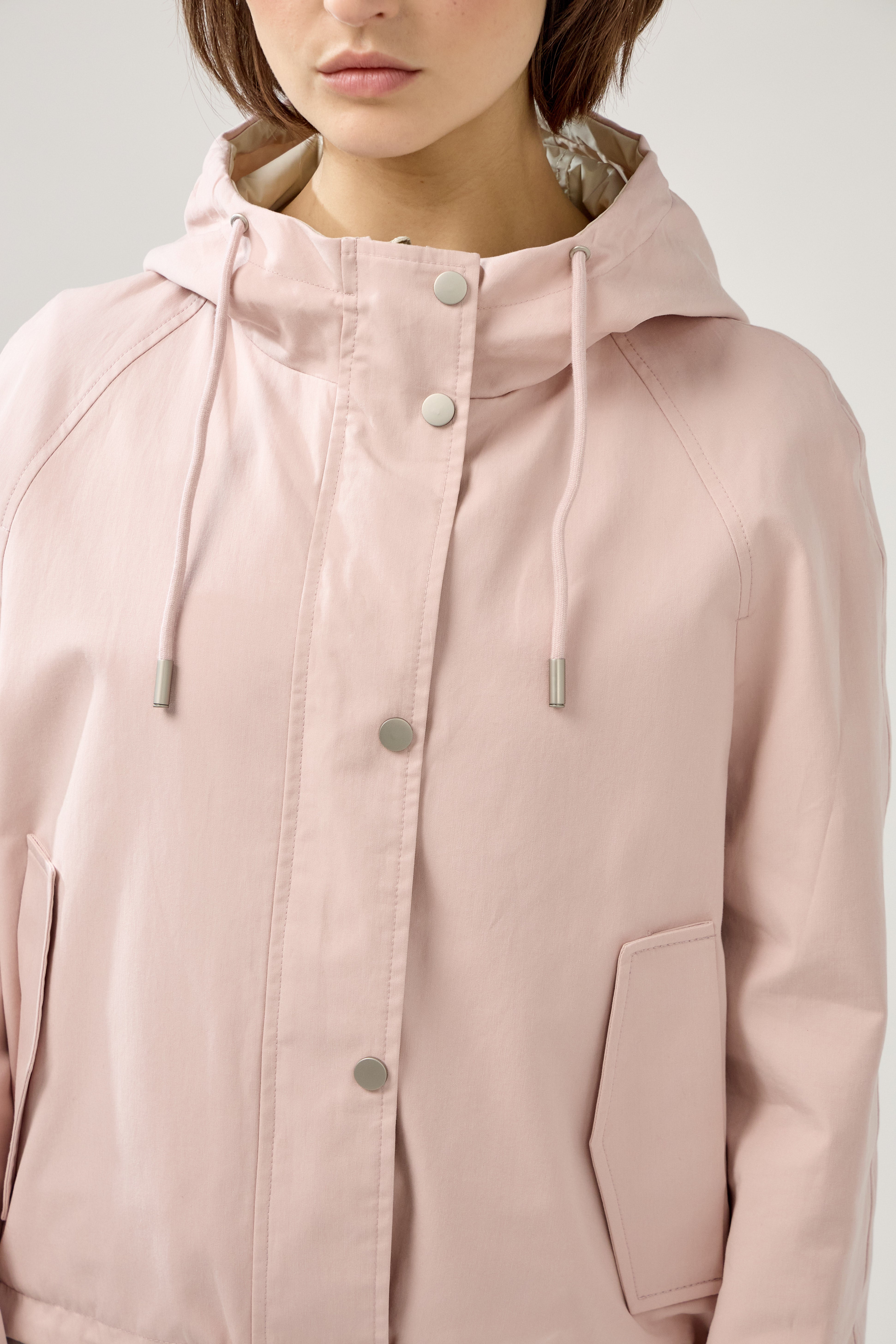 femme portant la parka Elunia réversible rose pâle/beige, fermeture à glissière et boutons à pressions, capuche à cordon, poche à rabats, bas ajustable, zoom col et boutons devant
#couleur_rose