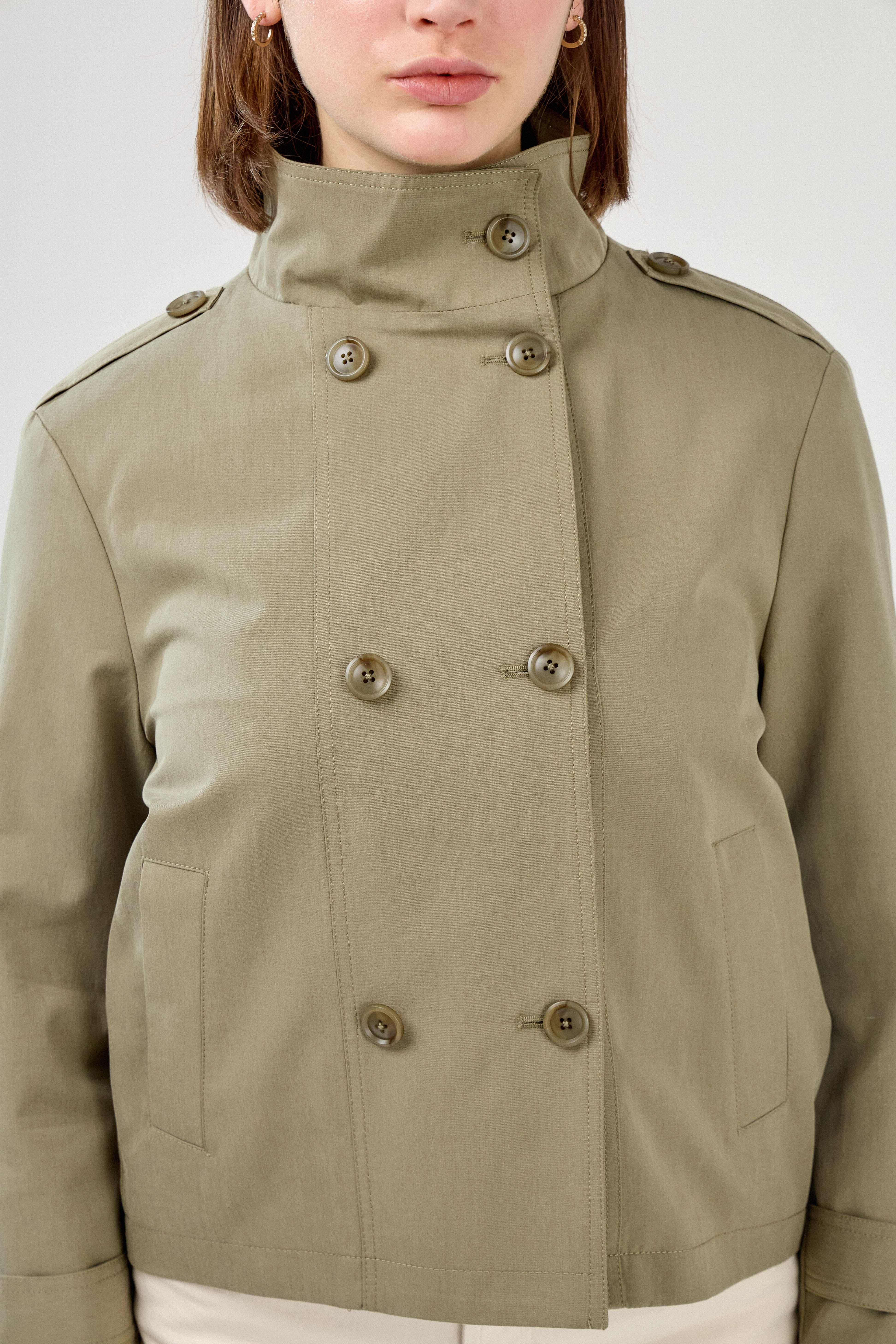 femme portant la veste trench col montant Lynara kaki clair, tenue chic féminine, fermeture à boutons et poches raglans, pattes de serrage décorative au poignets, dos
#couleur_kaki