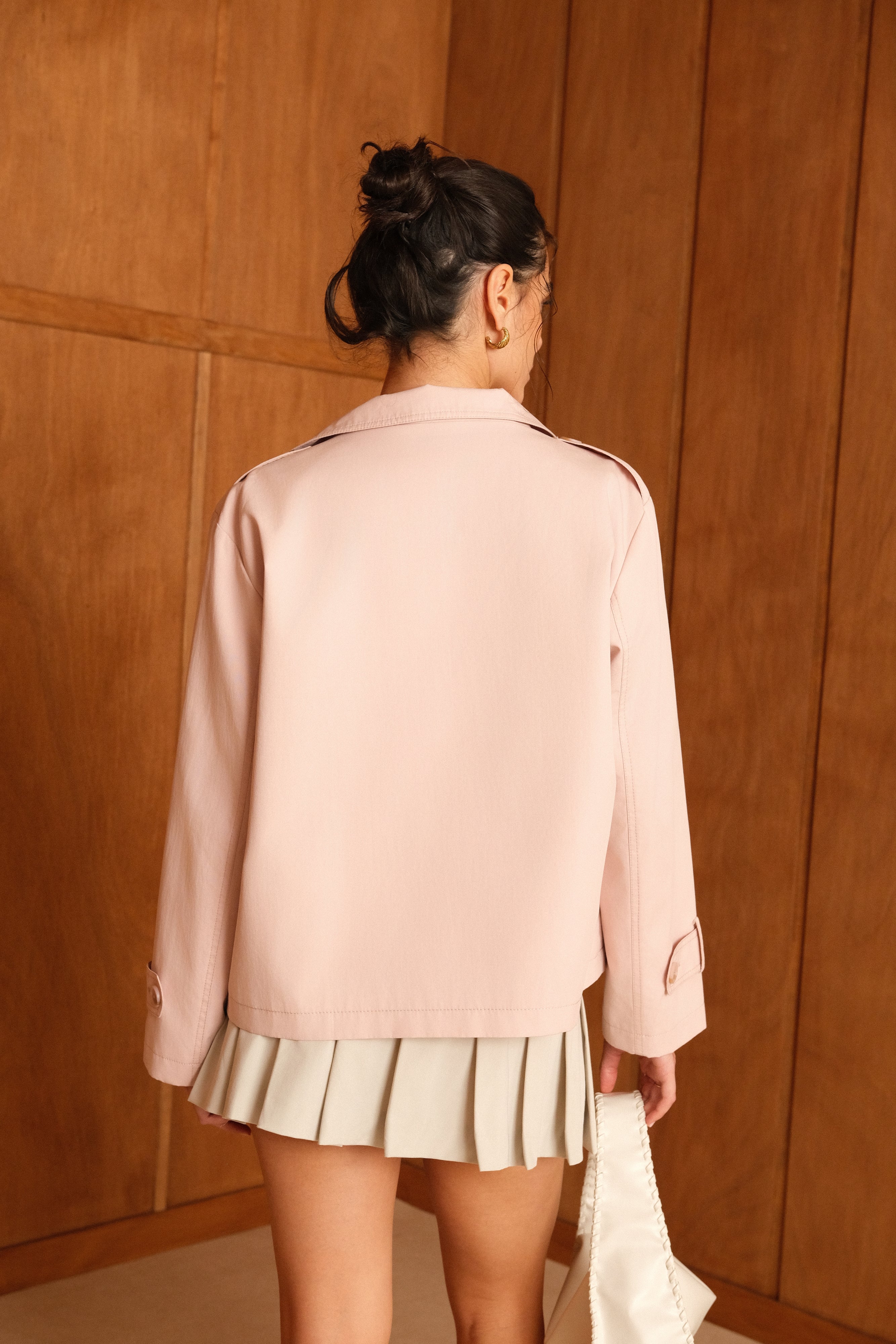 femme portant la veste trench col montant Lynara rose pâle, tenue chic féminine, pattes de serrage décorative au poignets et pattes d'épaules, dos
#couleur_rose