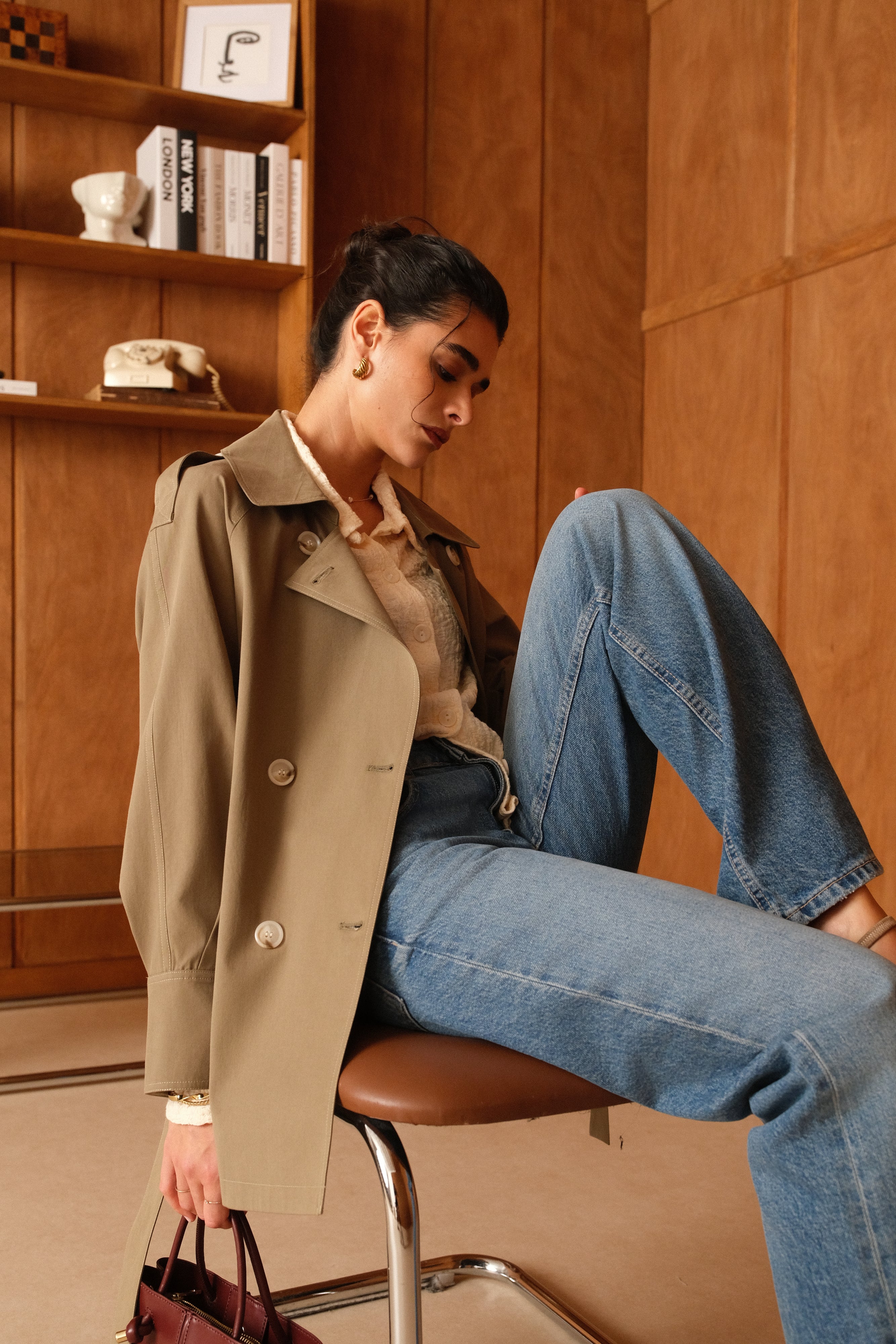 veste style trench mi-long kaki, col français/à revers, boutons, pattes d'épaules, couture milieu dos, fente et boutons poignets, ceinture, femme assise
#couleur_kaki