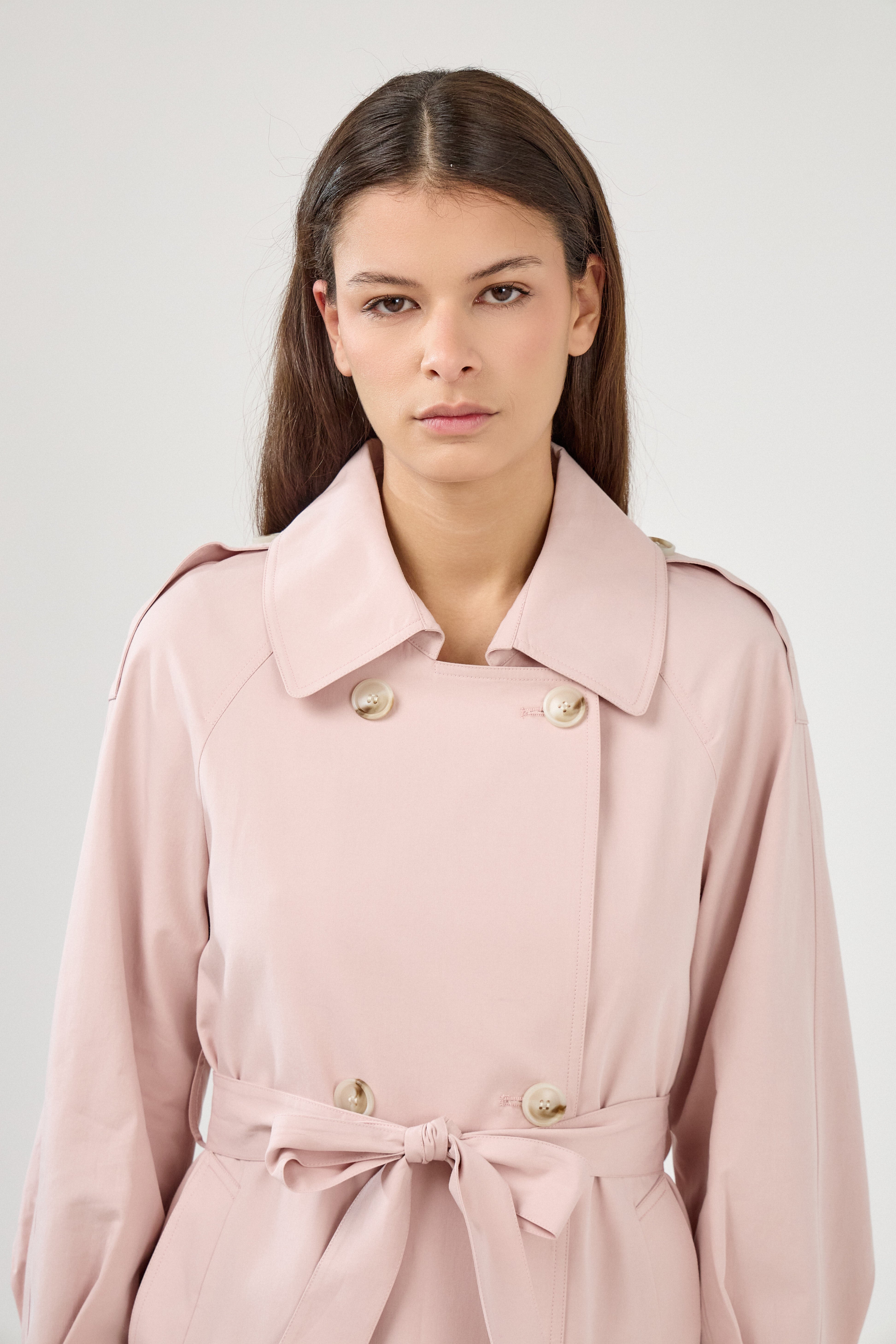 veste style trench mi-long rose pâle, col français, boutons, pattes d'épaules, ceinture et passants, poches raglans, zoom devant
#couleur_rose