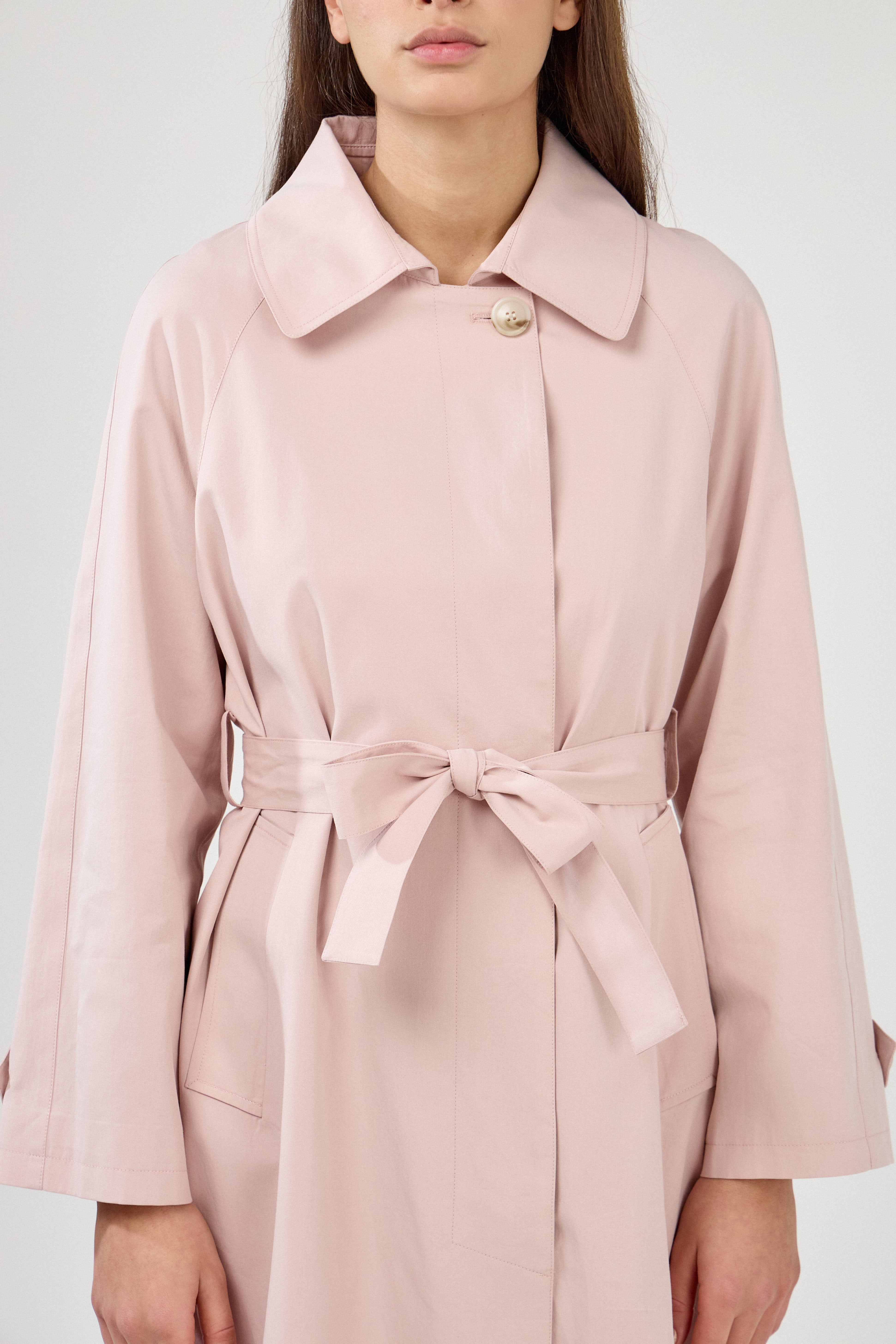 Trench mi-long, col à revers, fermeture à boutons, pattes de serrage aux poignets, ceinture et passants, poches raglans, zoom devant
#couleur_rose