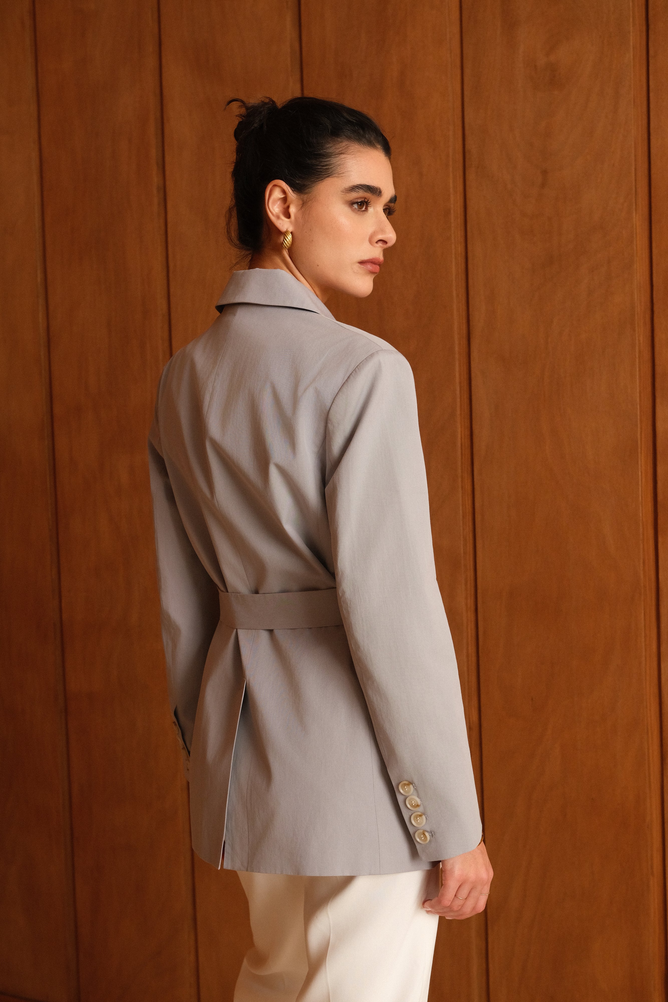 femme portant un blazer en coton bleu ciel, ceinture, fente bas milieu dos, col à revers, taille droit coupe élégante, poignets à boutons, dos
#couleur_ciel