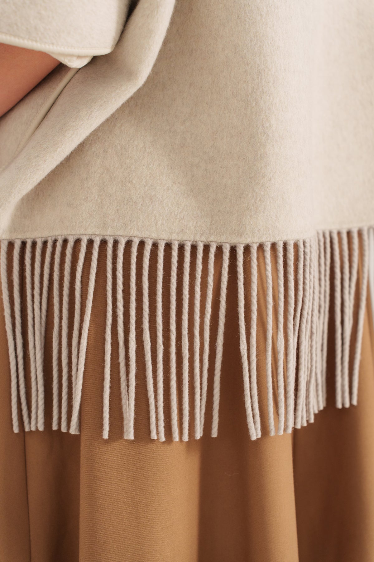 Cape en laine camel pour femme à capuche avec franges et fermeture zippée – Escandelle - gros plan
#couleur_beige 