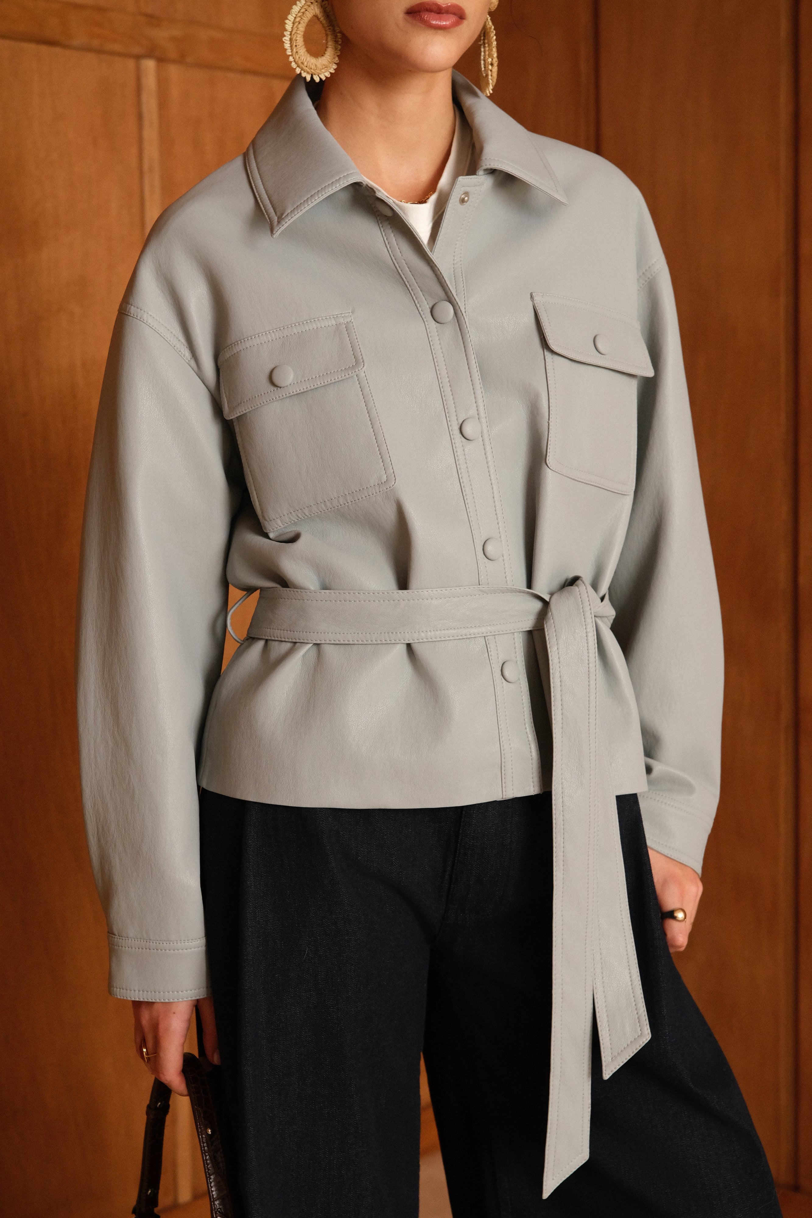 veste en similicuir à ceinture, col français, poches plaquées à rabats boutonnées poitrine, boutonnière avant boutons pressions, zoom devant
#couleur_ciel