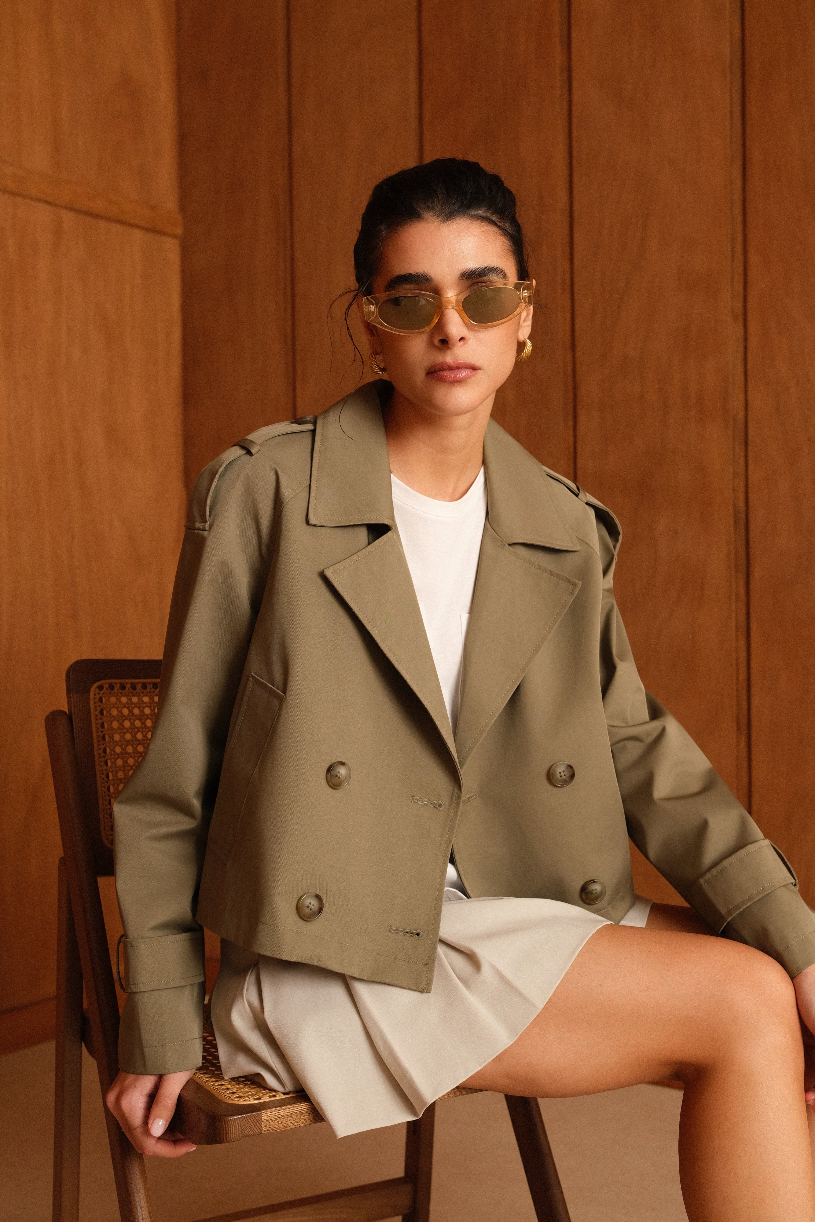 trench court à col à revers, poches raglans, pattes d'épaule et poignets, fermeture à 4 boutons, zoom devant femme assise
#couleur_kaki 