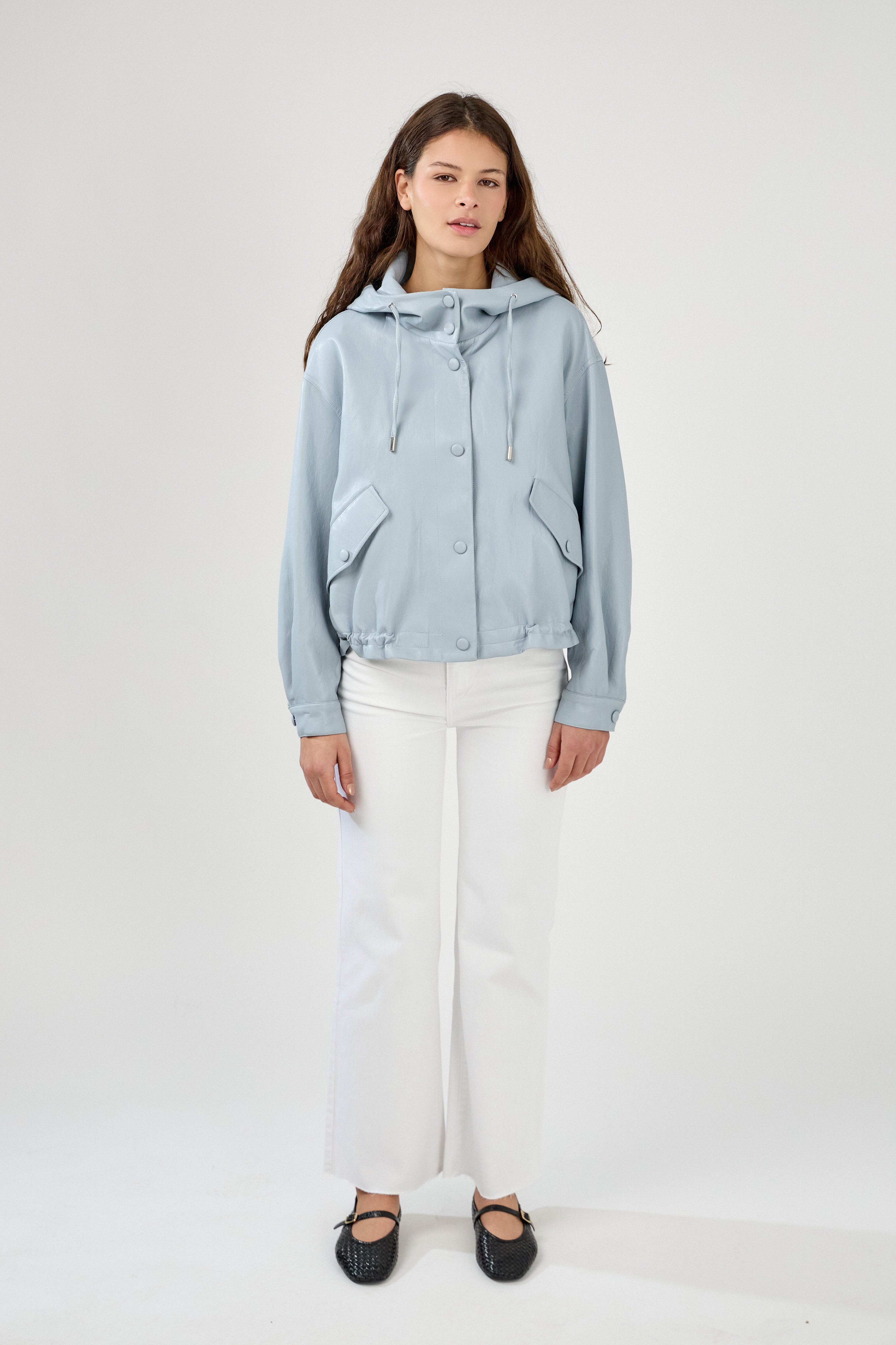 femme portant un blouson en similicuir, fermeture à boutons pression, manches larges refermées par un bouton au poignet, capuche à cordons, poches à rabats et bas ajustable avec élastique, devant
#couleur_ciel