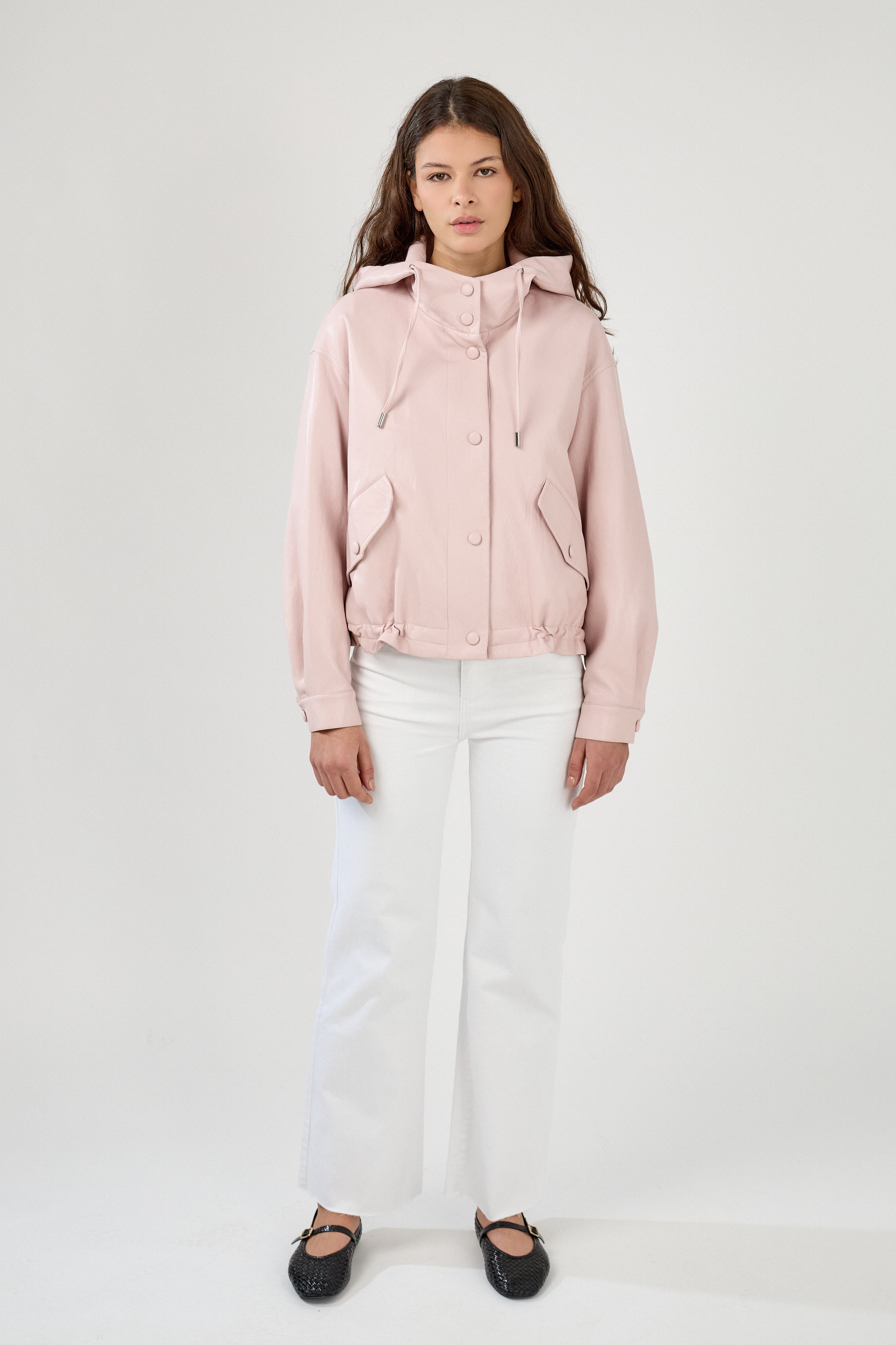 femme portant un blouson en similicuir, fermeture à boutons pression, manches larges refermées par un bouton au poignet, capuche à cordons, poches à rabats et bas ajustable avec élastique, devant
#couleur_rose