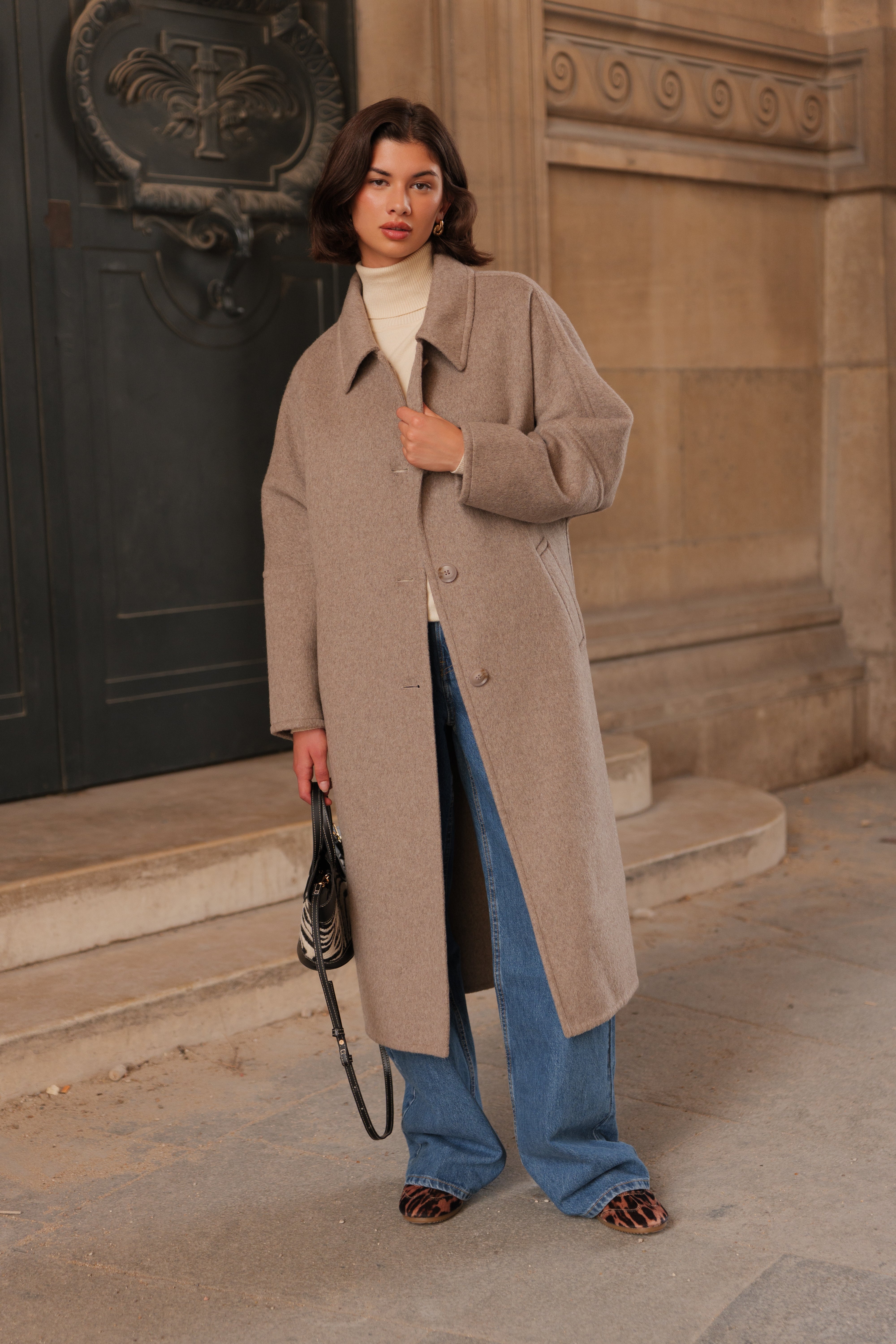 Manteau long femme en laine beige CELESTE, coupe droite et ample, col chemise et poches latérales, porté avec un pull écru et un pantalon en jean.
#couleur_beige