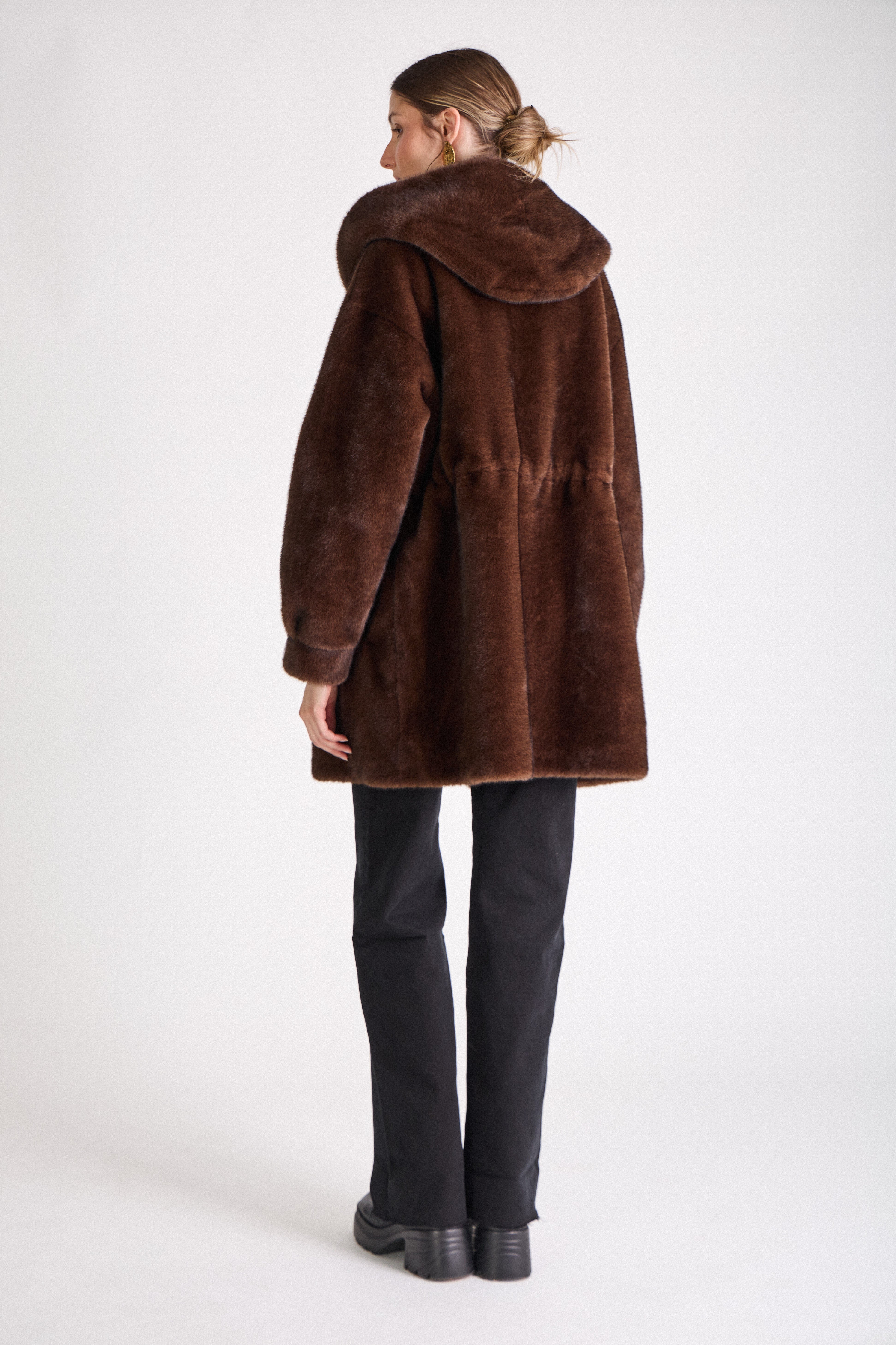 Femme portant le manteau long GRACE en fausse fourrure choco, coupe droite et capuche
#couleur_choco