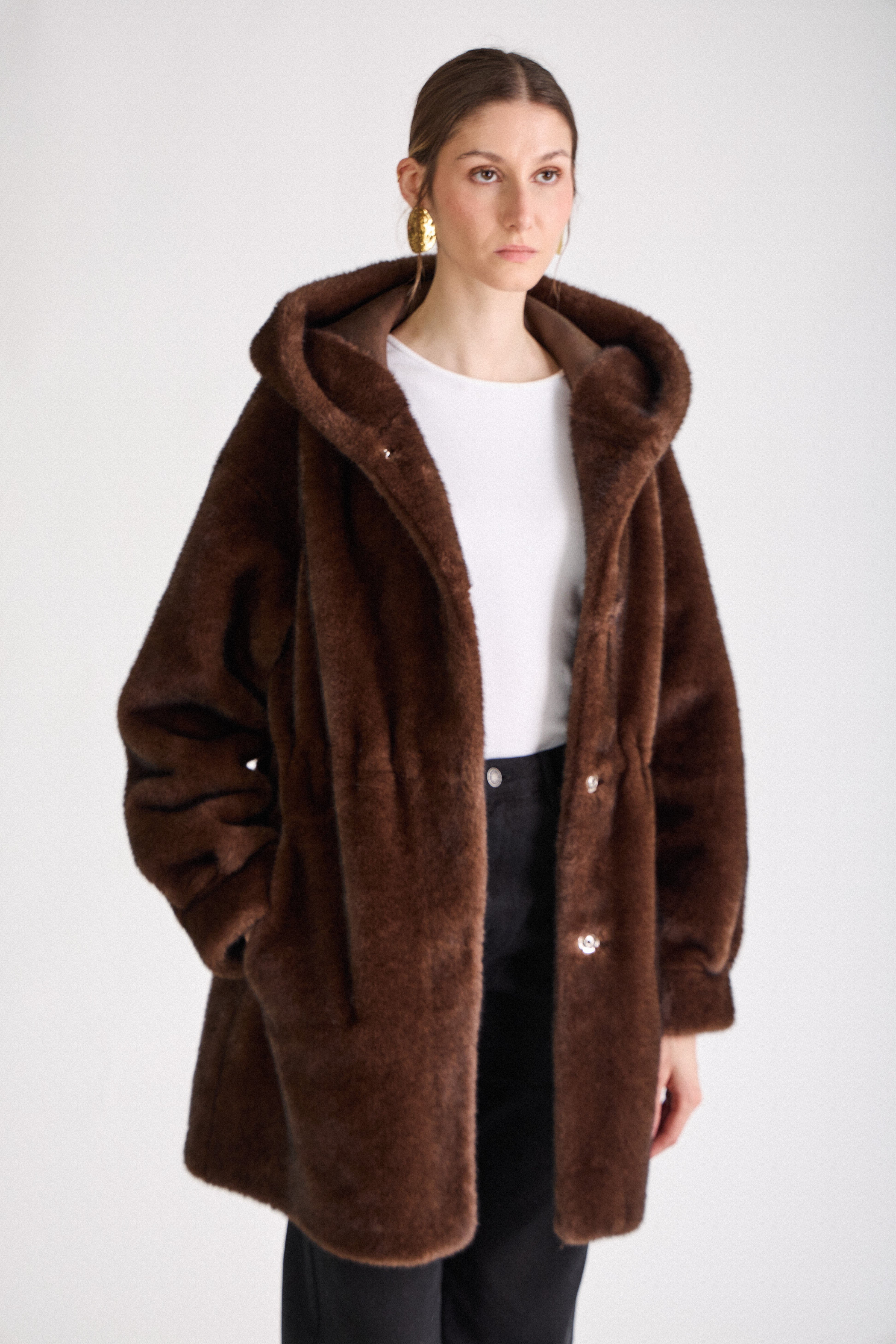 Femme portant le manteau long GRACE en fausse fourrure choco, coupe droite et capuche
#couleur_choco